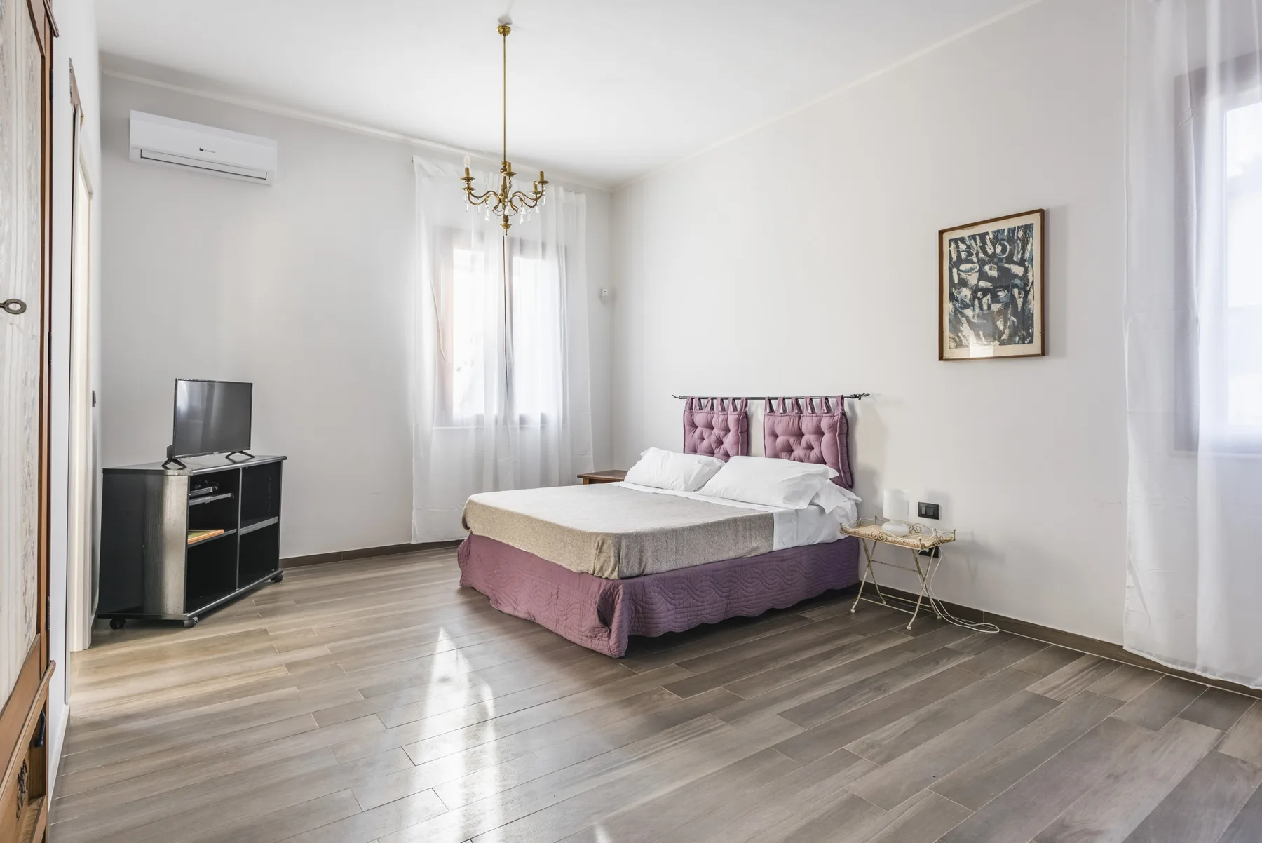Un dormitorio con una cama, un televisor y una lámpara de araña.