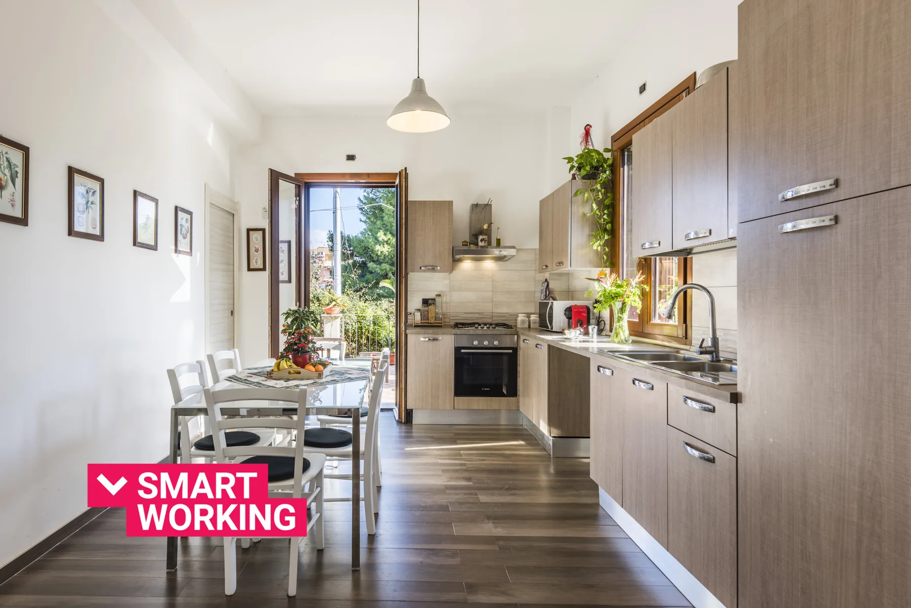 Una cocina luminosa con una mesa de comedor junto a una puerta abierta hacia la vegetación.