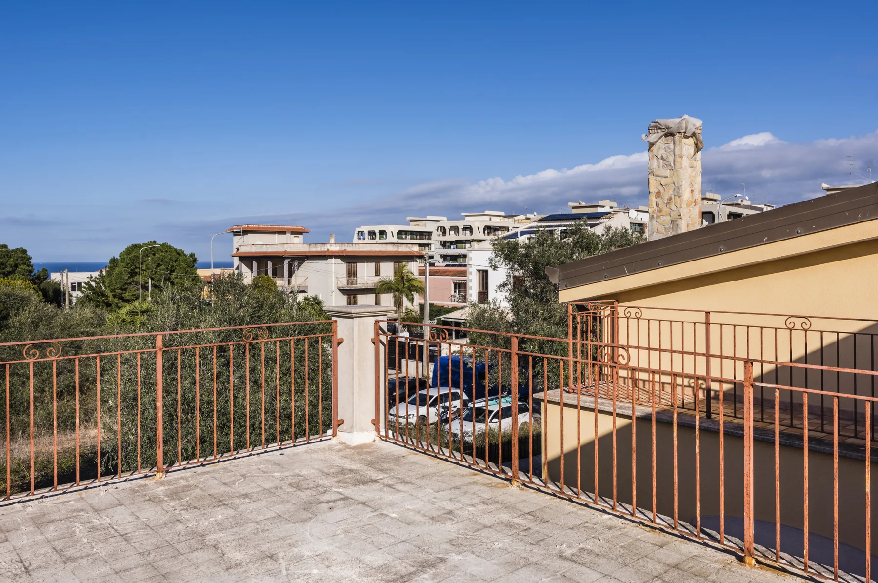 Una terraza en la azotea da a edificios cercanos y una franja de mar.