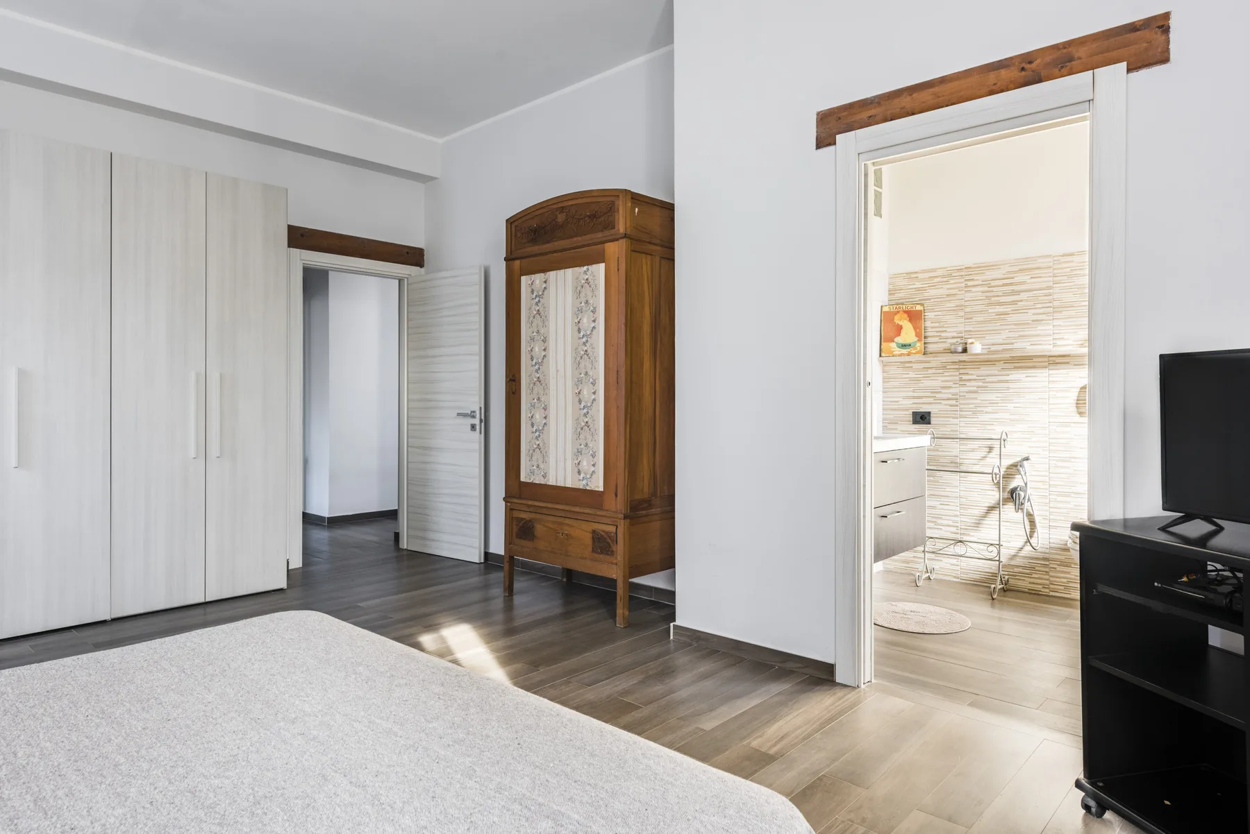Un dormitorio luminoso con un armario grande y una puerta abierta al baño.