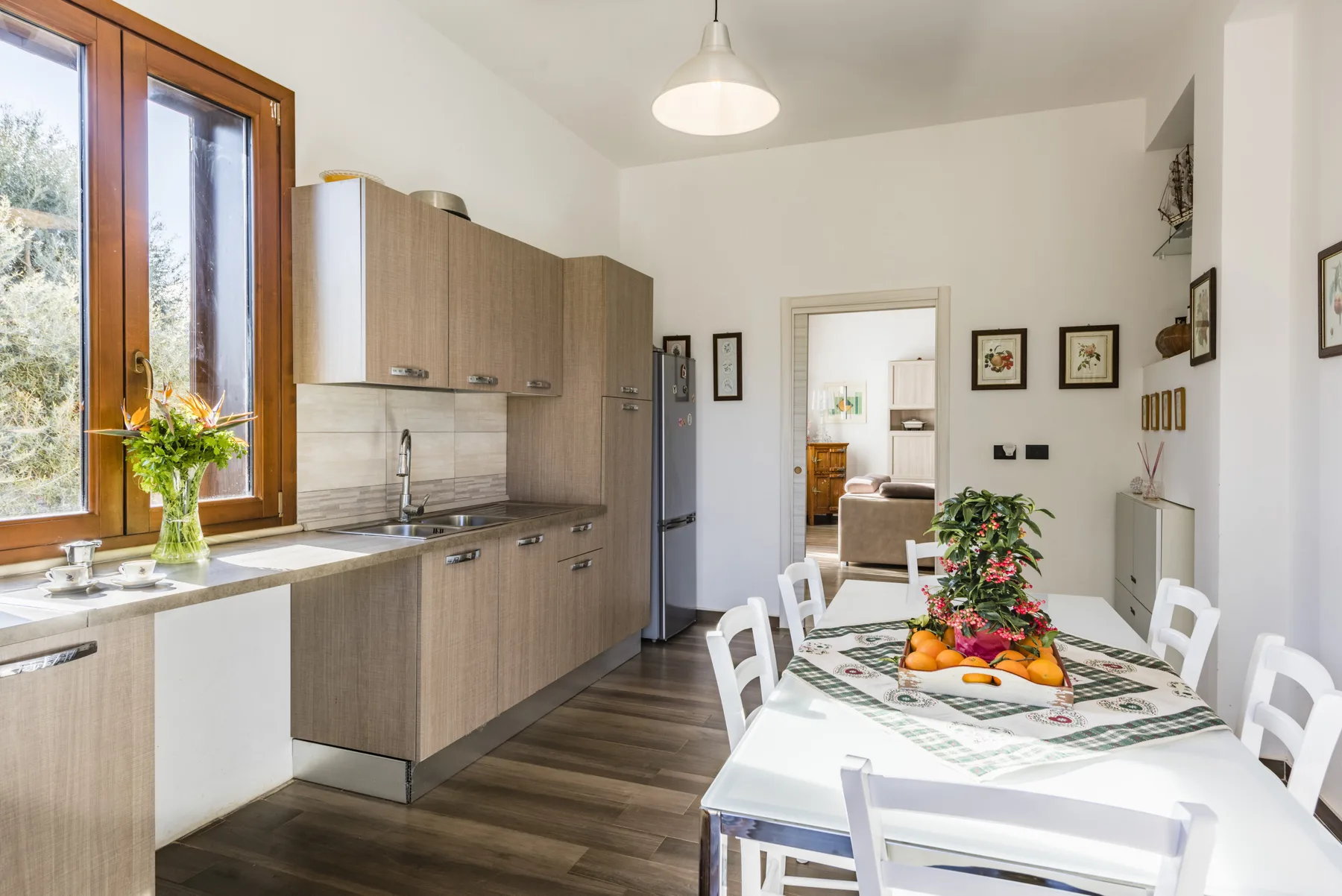 Una luminosa cocina y comedor con una mesa larga adornada con fruta.