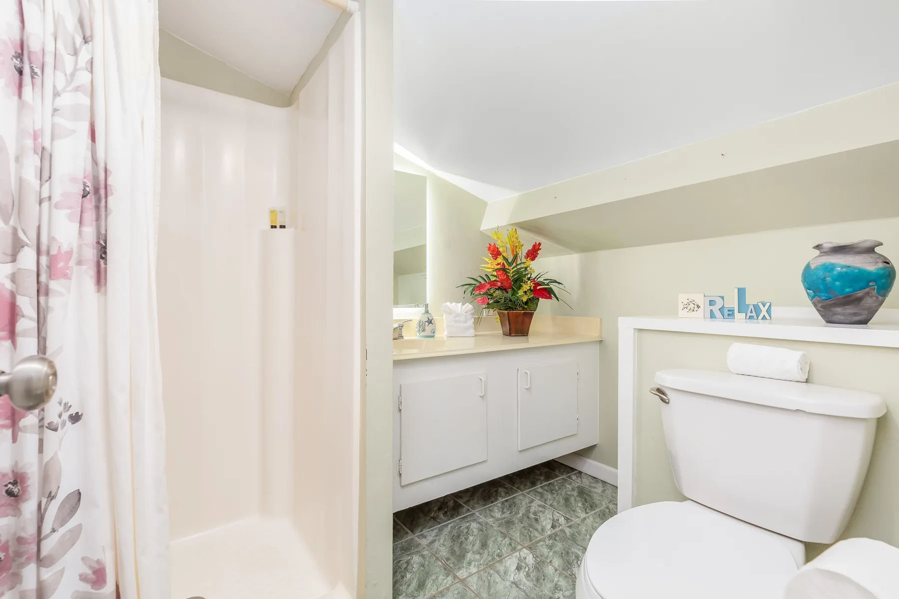 A bathroom with a shower, sink vanity, and toilet.