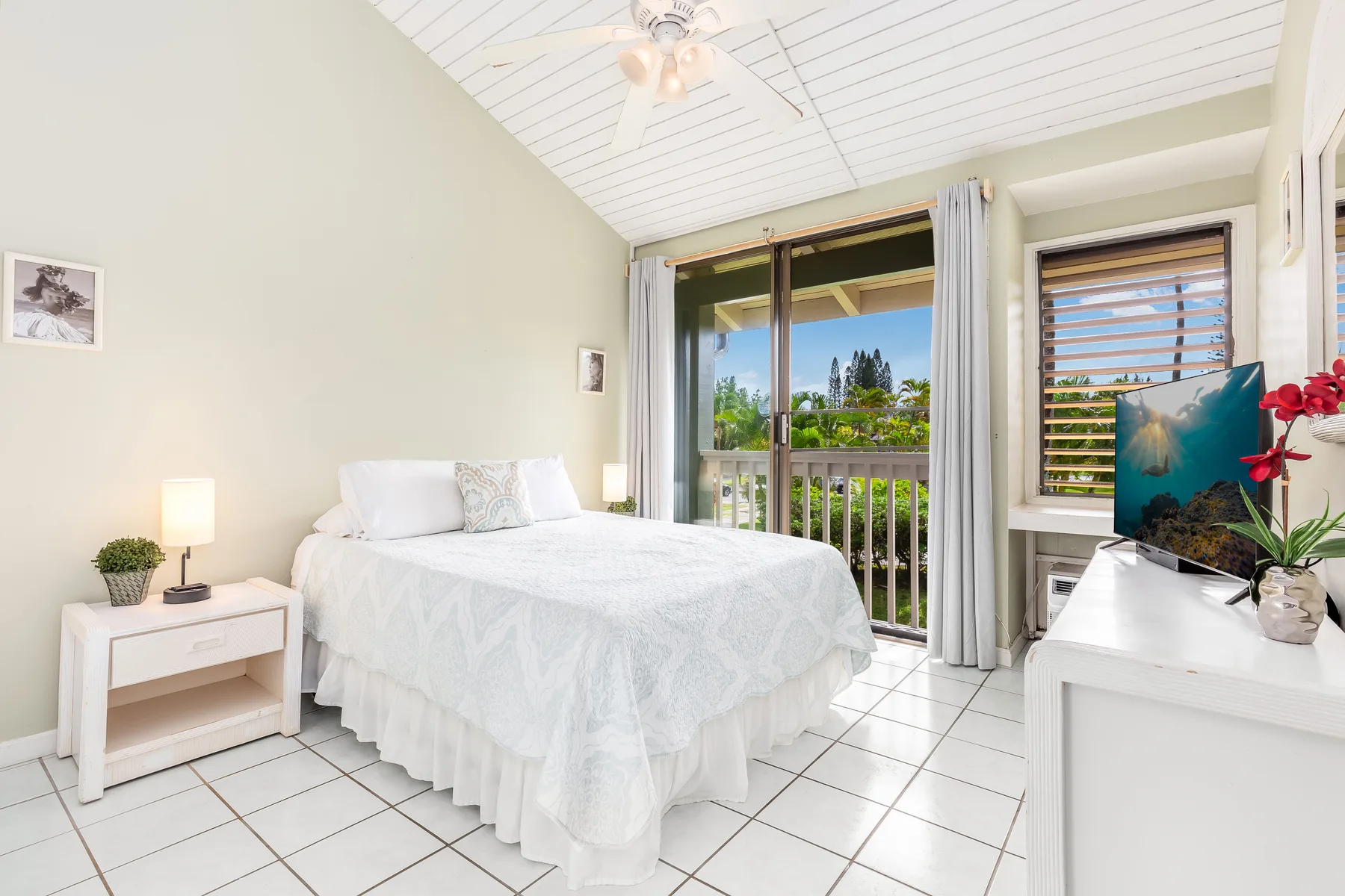 A bright bedroom with a bed beside glass doors opening onto a balcony.