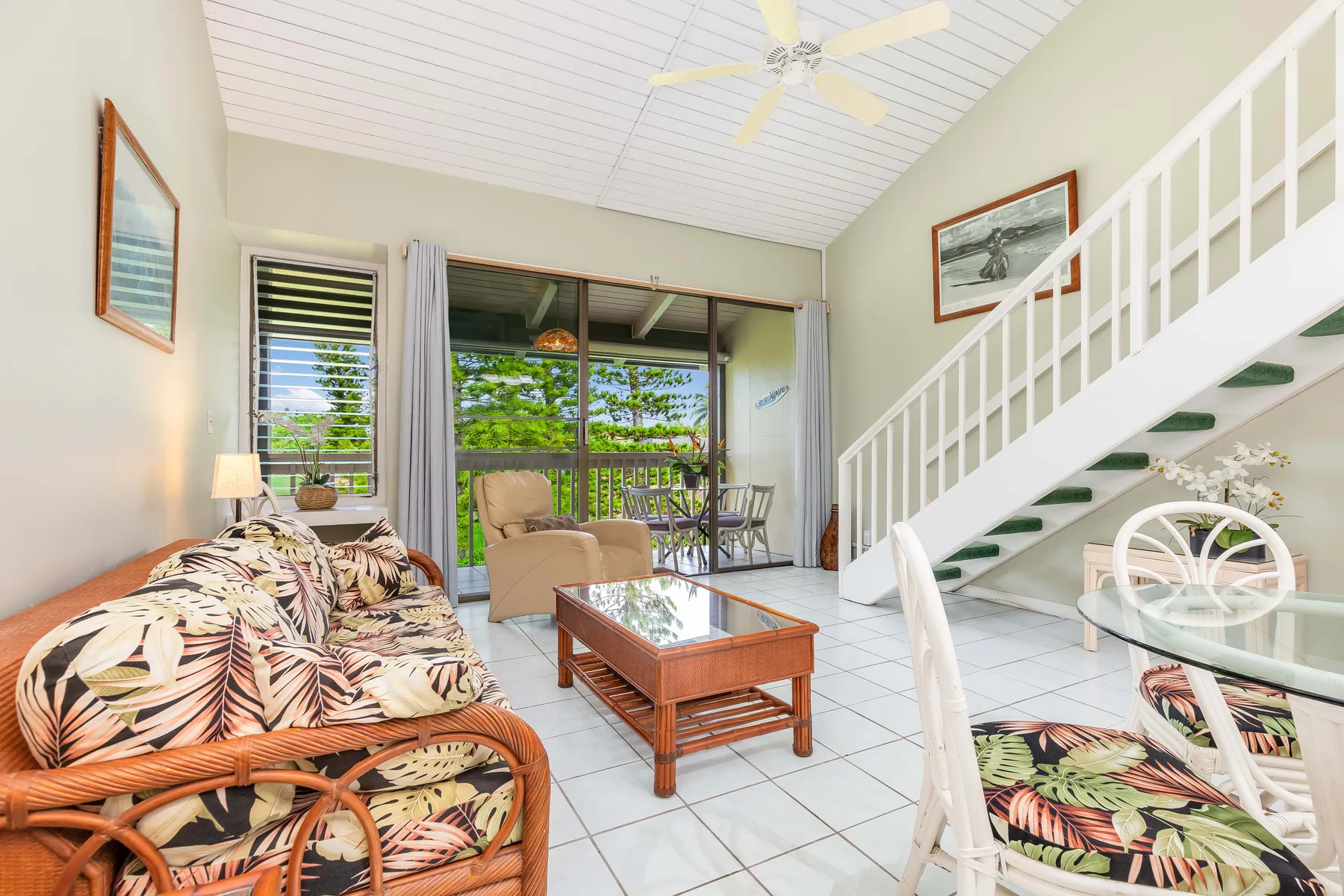 A bright living room with patterned seating, a coffee table, and a staircase.