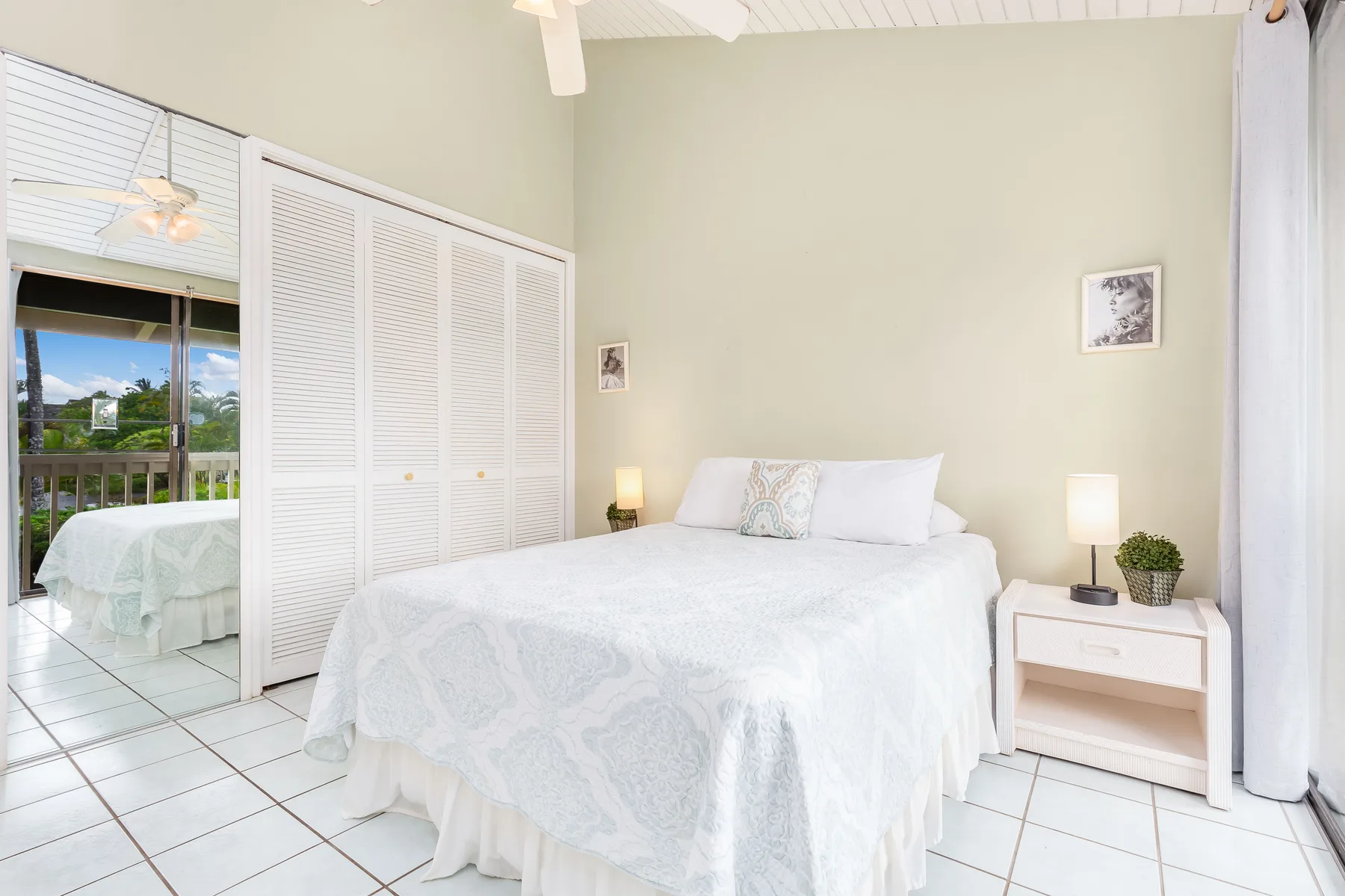 A bright bedroom with a bed, bedside tables, and mirrored closet doors.
