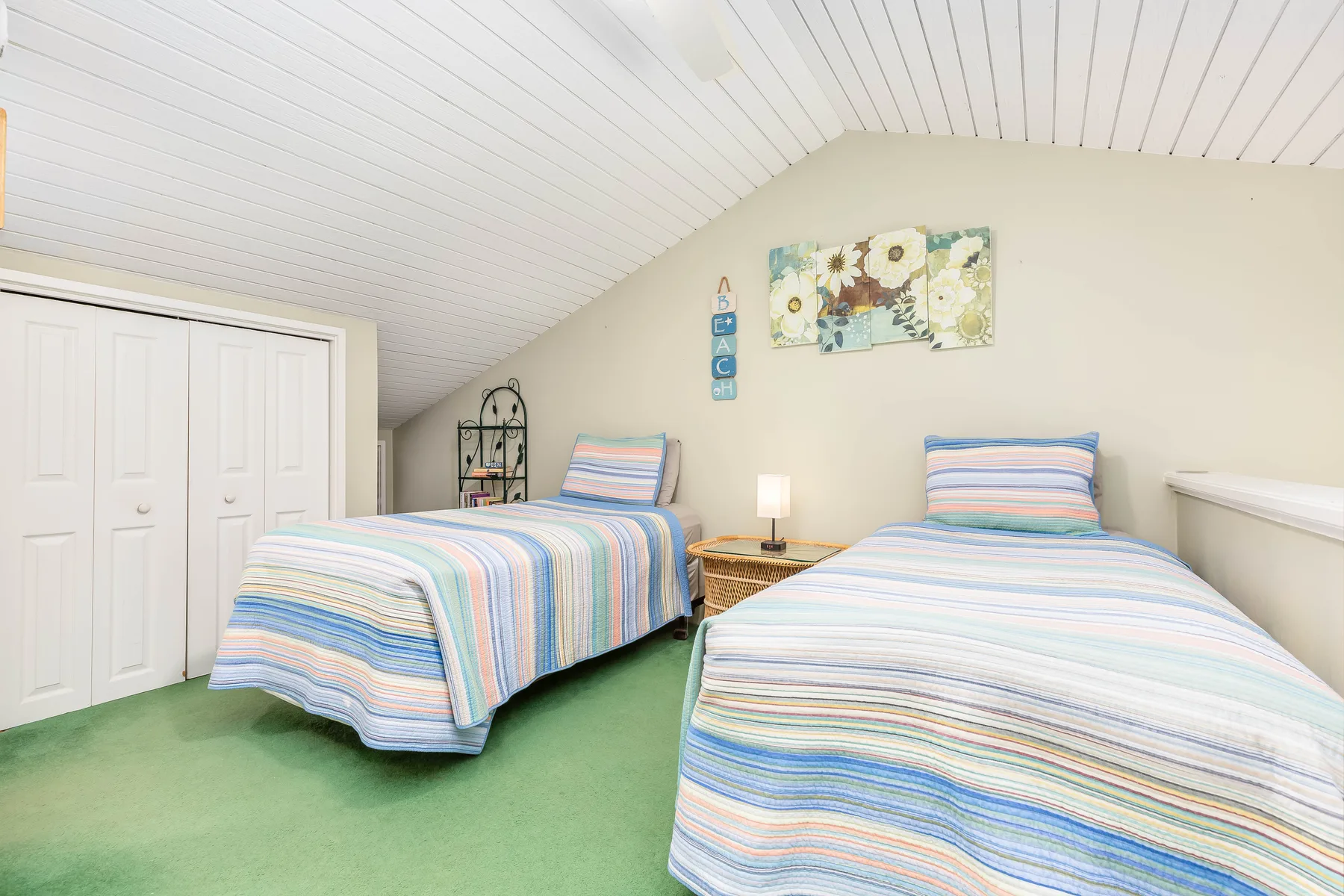 A bedroom with two beds covered in striped bedding.