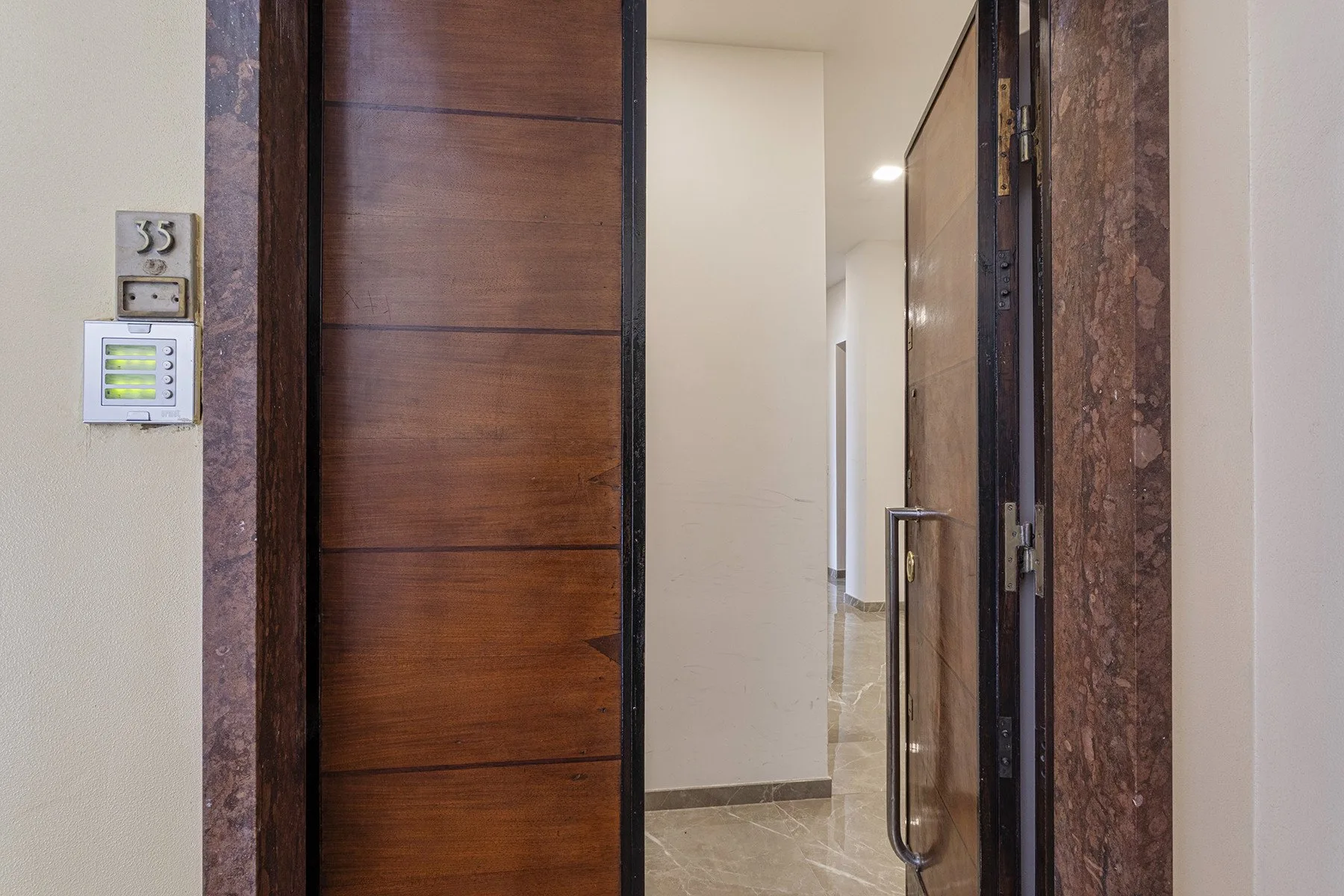 An open wooden entrance door leads into a bright interior hallway.