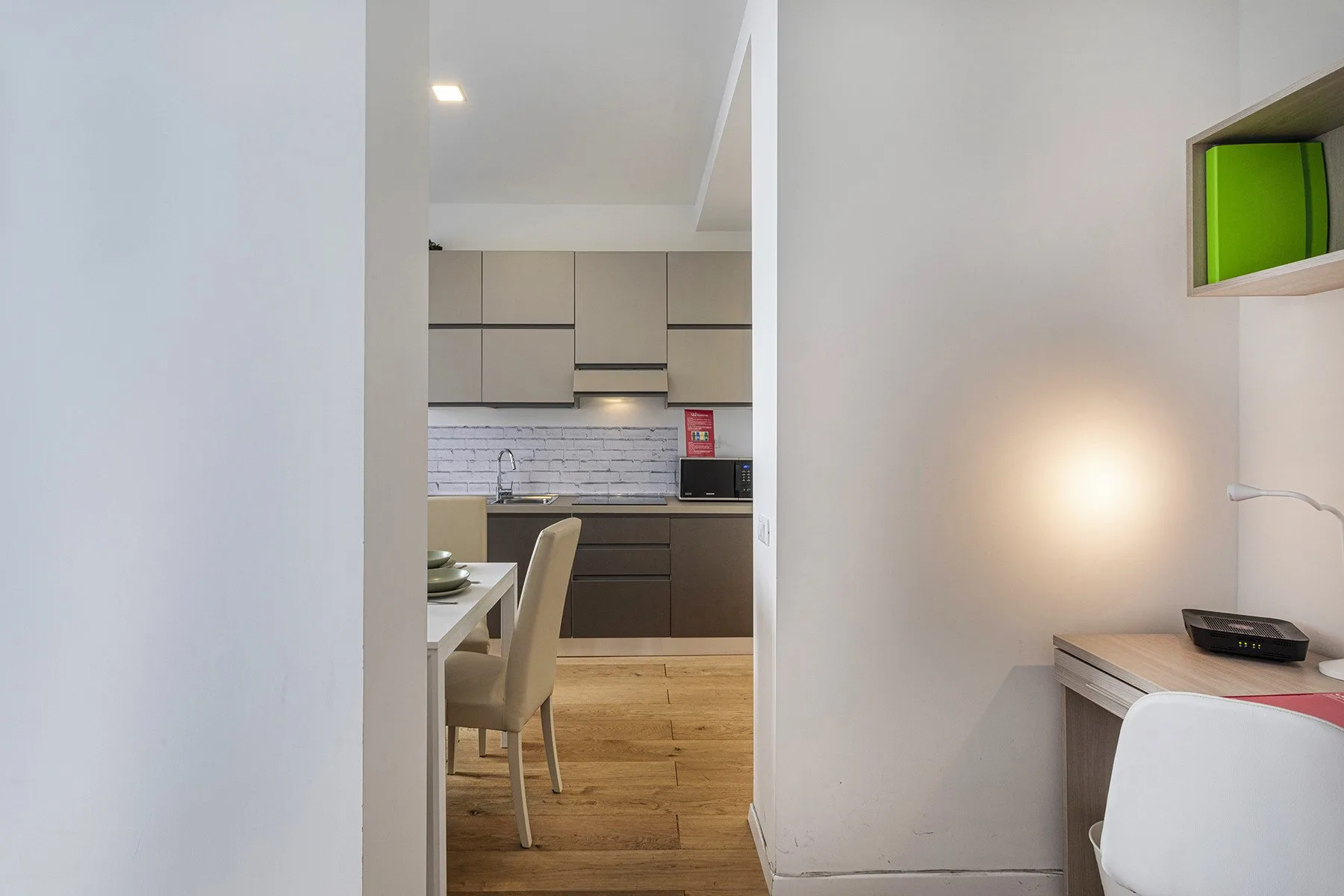 A dining area opens onto a modern kitchen with light wood flooring.