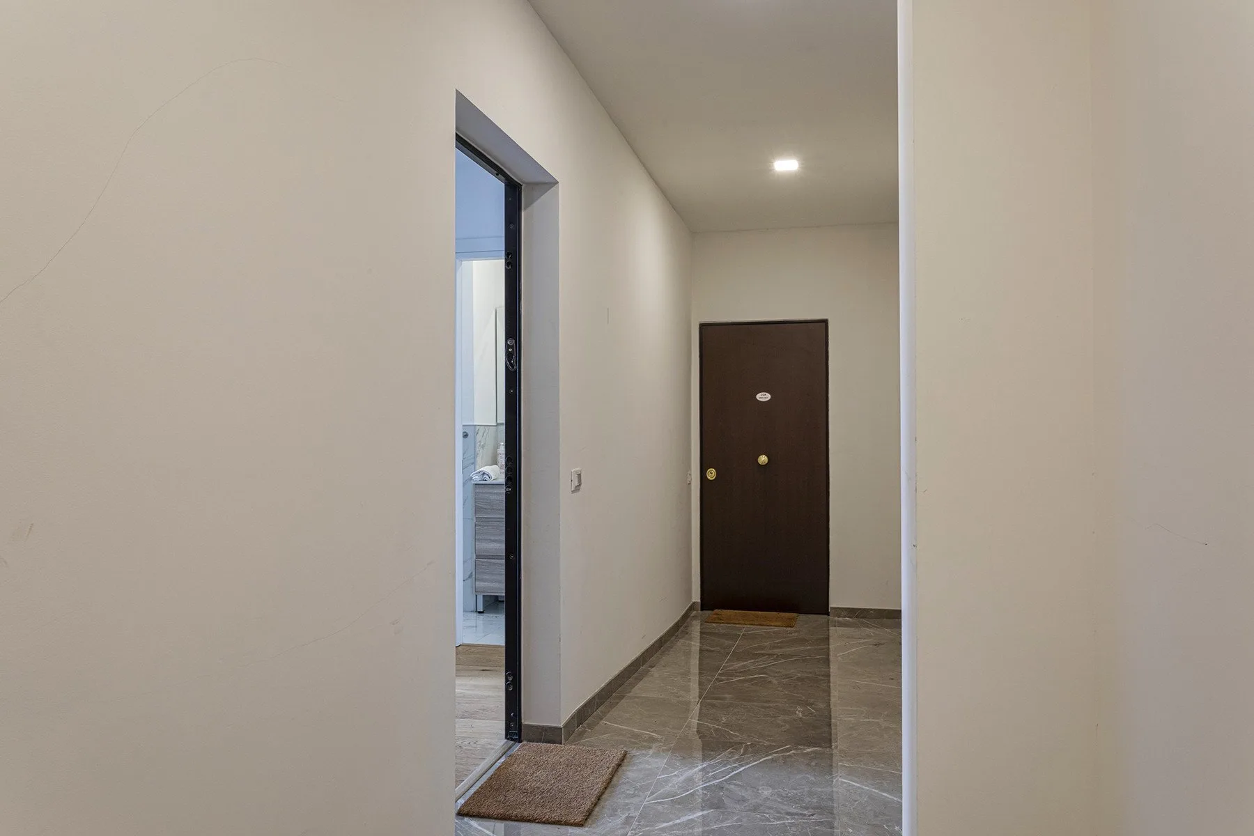 A hallway with a dark entrance door and an open doorway.