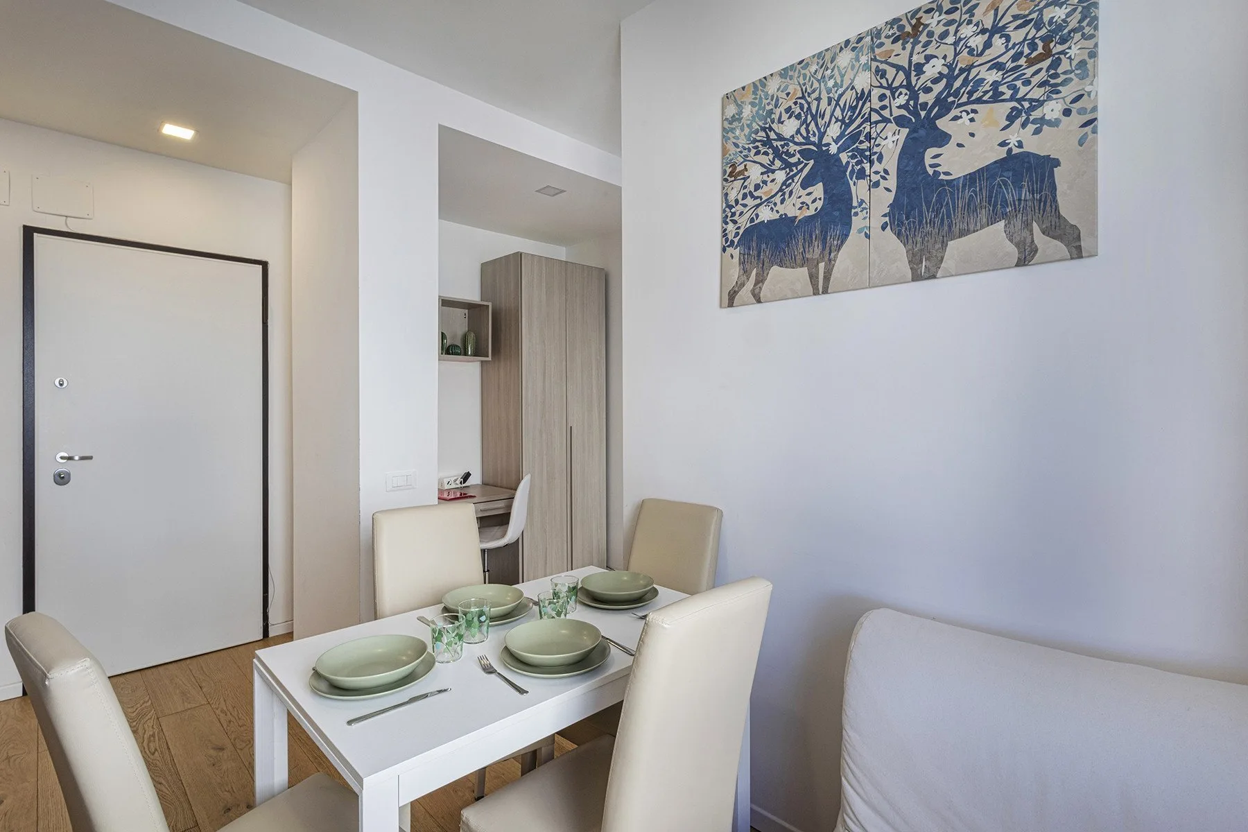 A dining area with a set table and framed artwork on the wall.