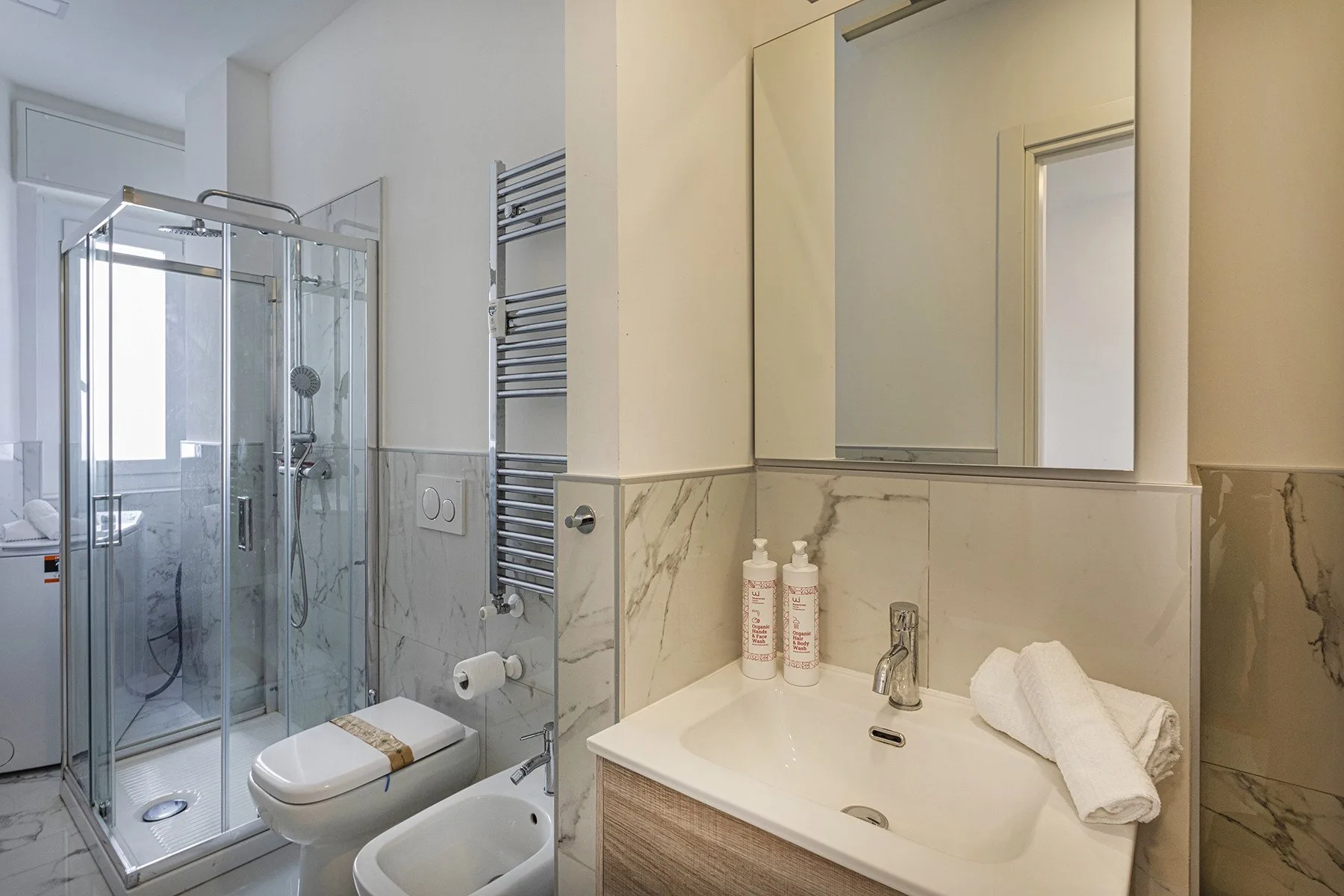 A bright bathroom with a glass shower and a sink beneath a large mirror.