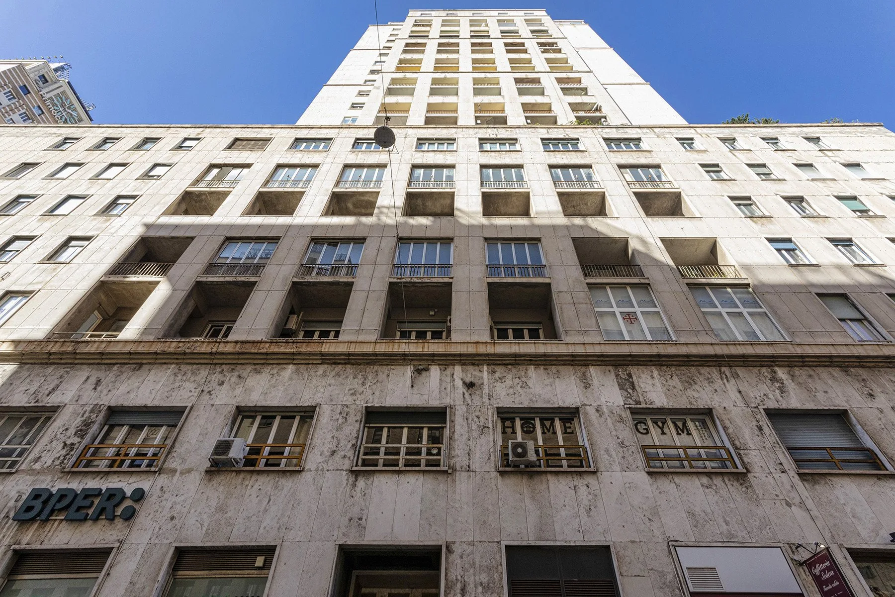A tall building facade rises against a clear blue sky.