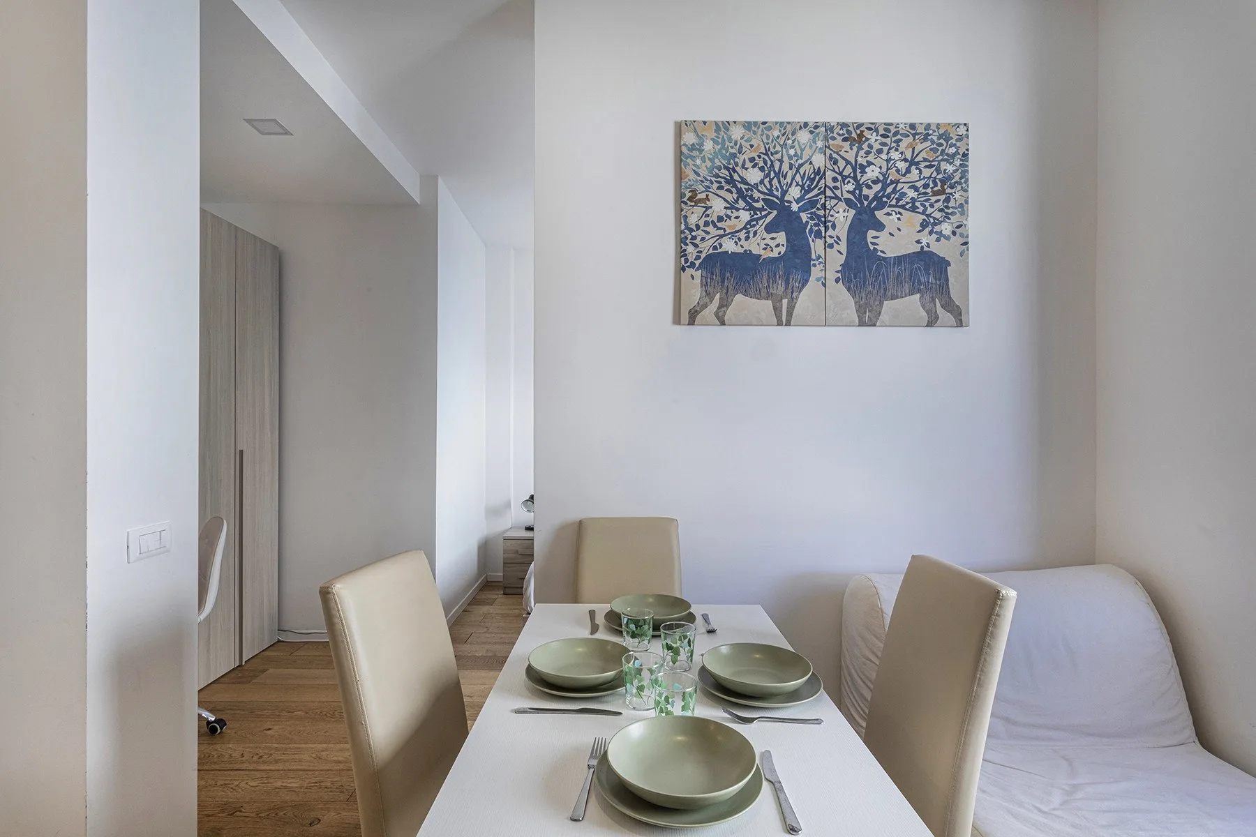 A dining area with a set table beside a sofa.