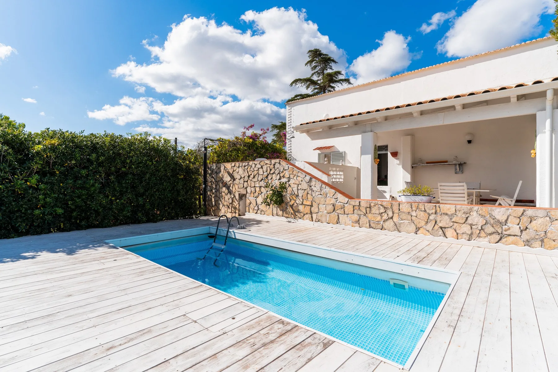 An outdoor swimming pool beside a covered patio and white deck.