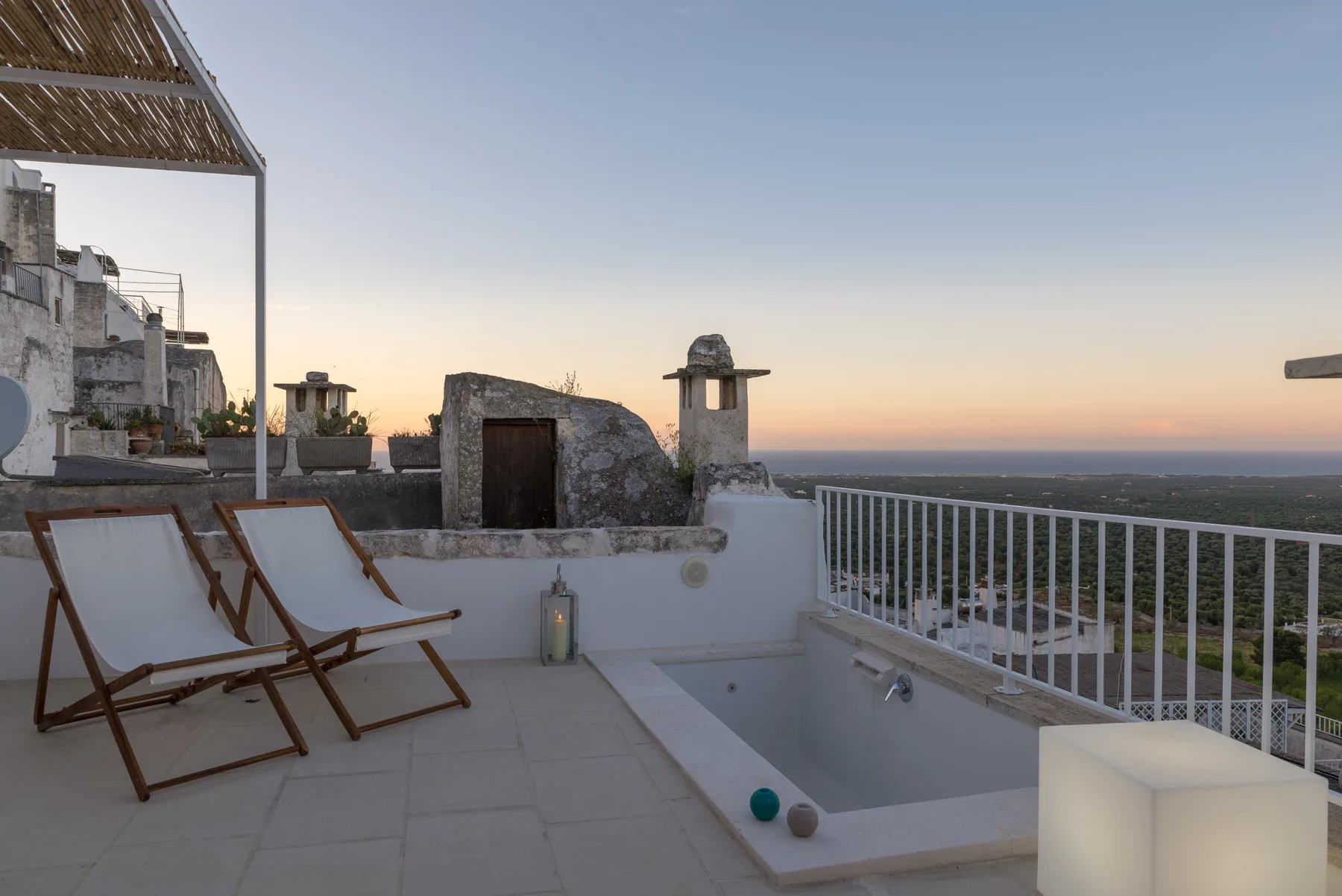 Una terraza en la azotea al atardecer cuenta con asientos y una pequeña piscina de inmersión.