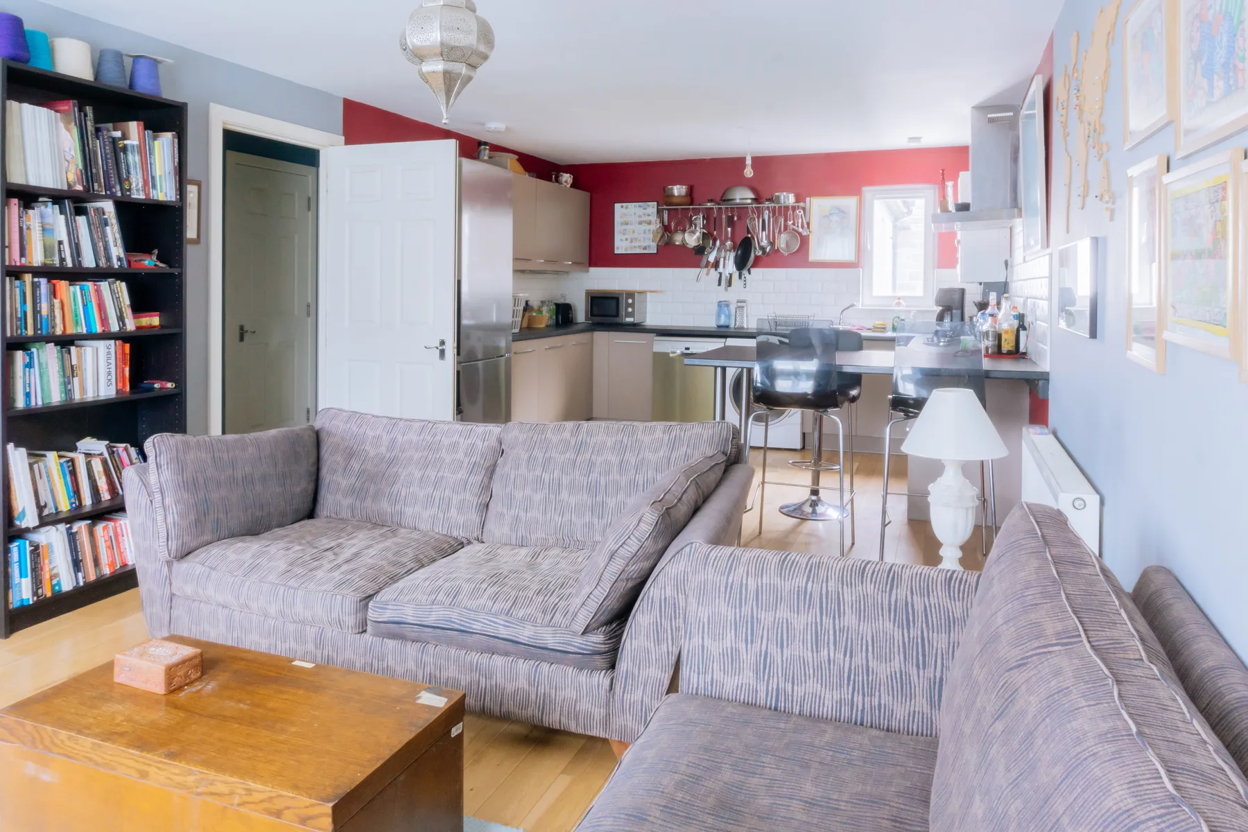 Una sala de estar con asientos grises, una mesa de centro y una cocina abierta.