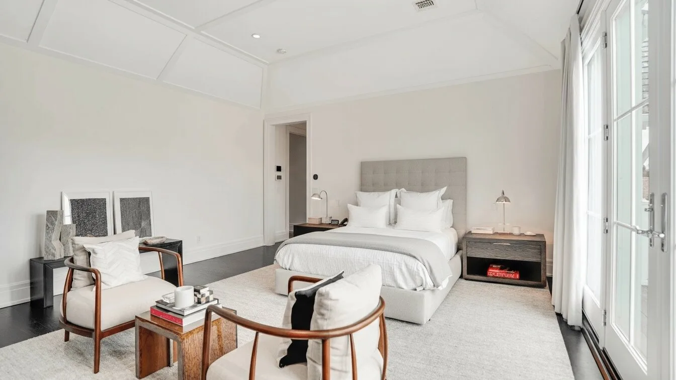 Un dormitorio luminoso con una cama bien hecha y grandes ventanas.
