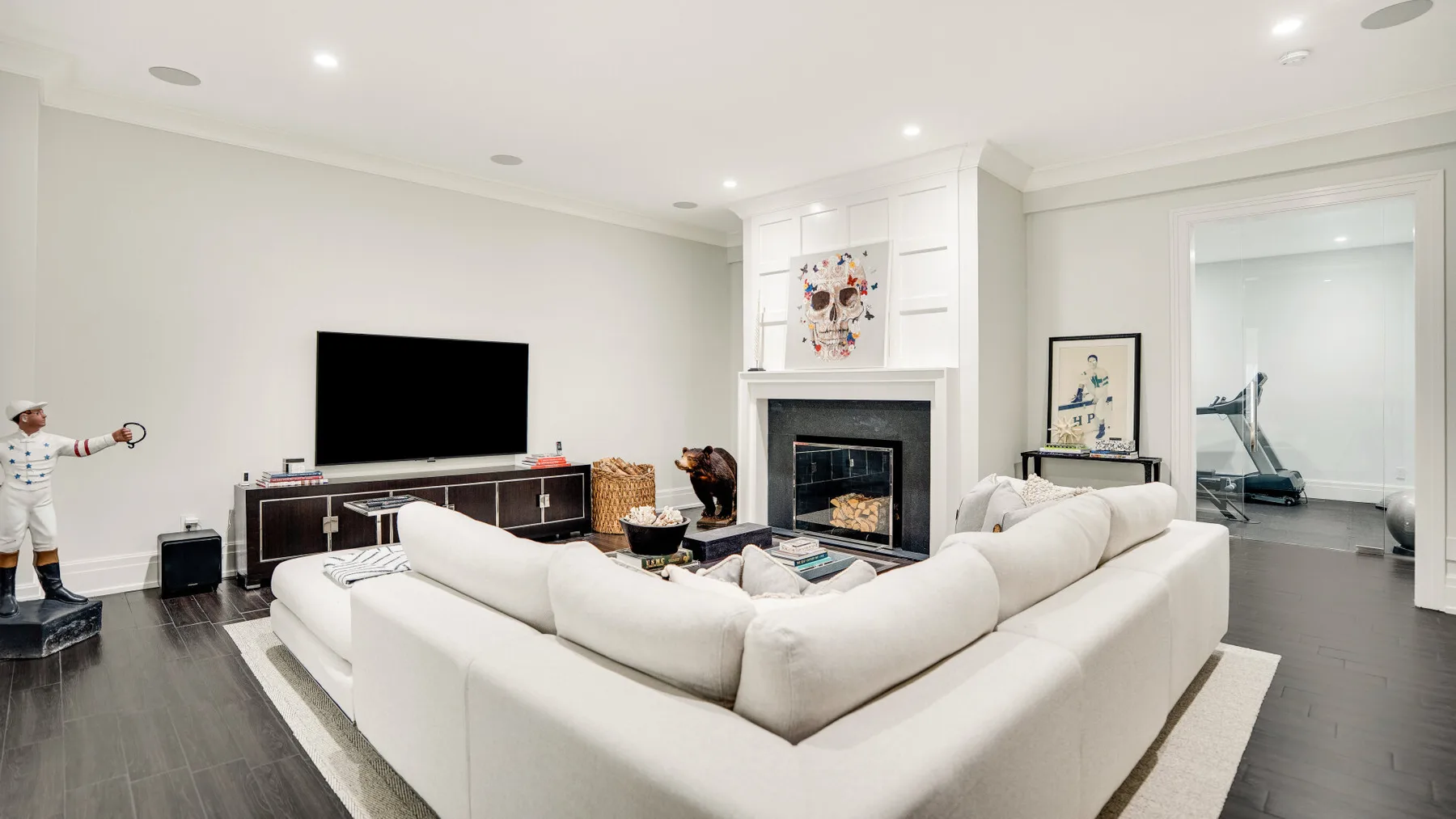 Una sala luminosa con asientos blancos, un televisor y una chimenea.