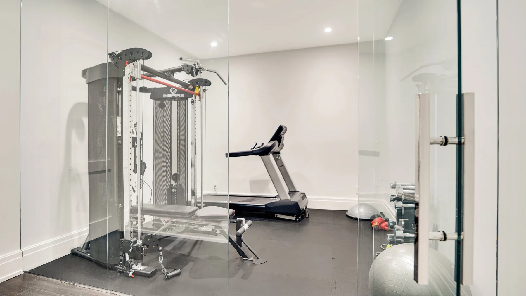Un gimnasio con equipo de pesas, una cinta de correr y balones de ejercicio.