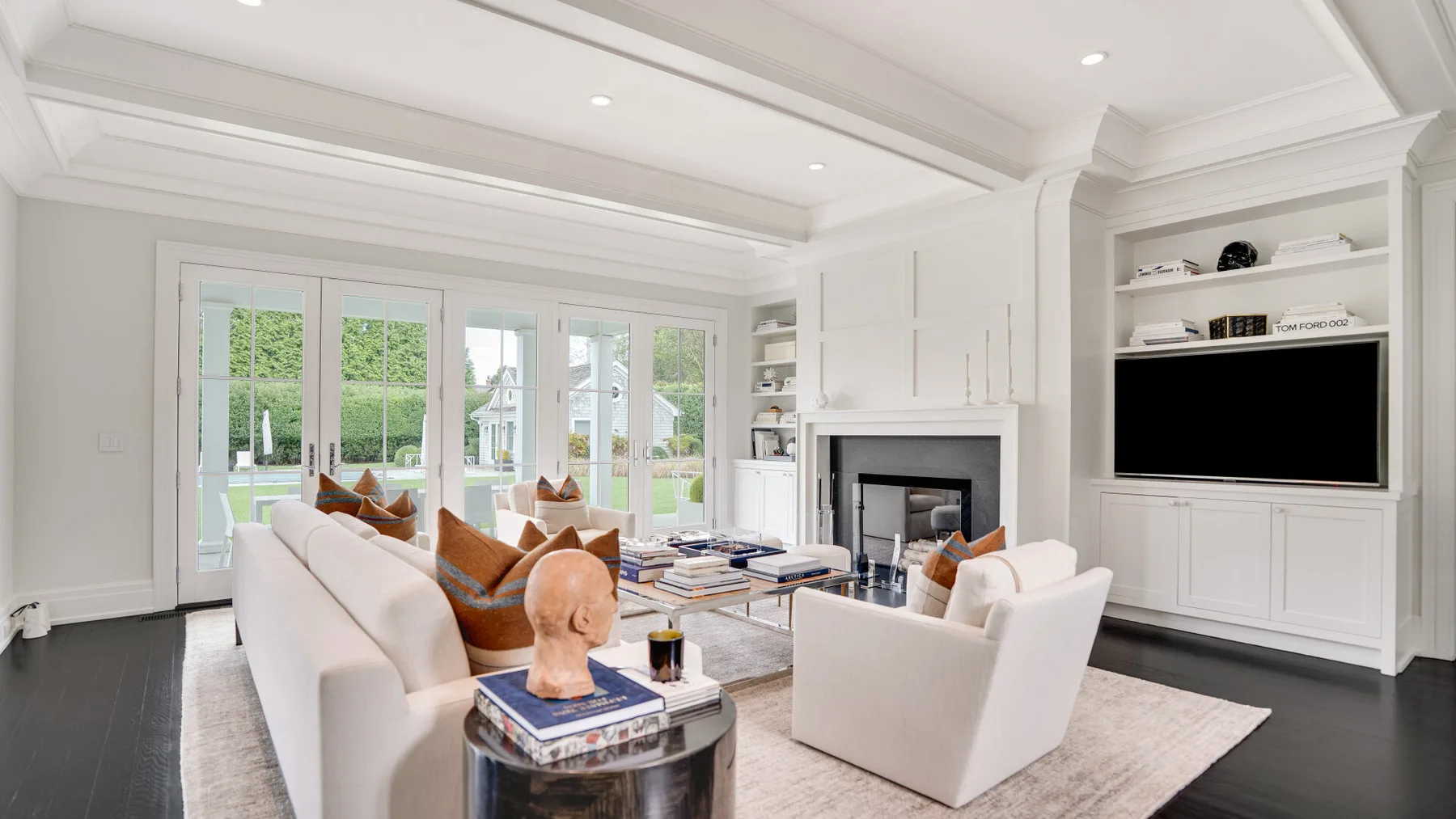 Una sala luminosa con asientos blancos y una chimenea junto a un televisor.