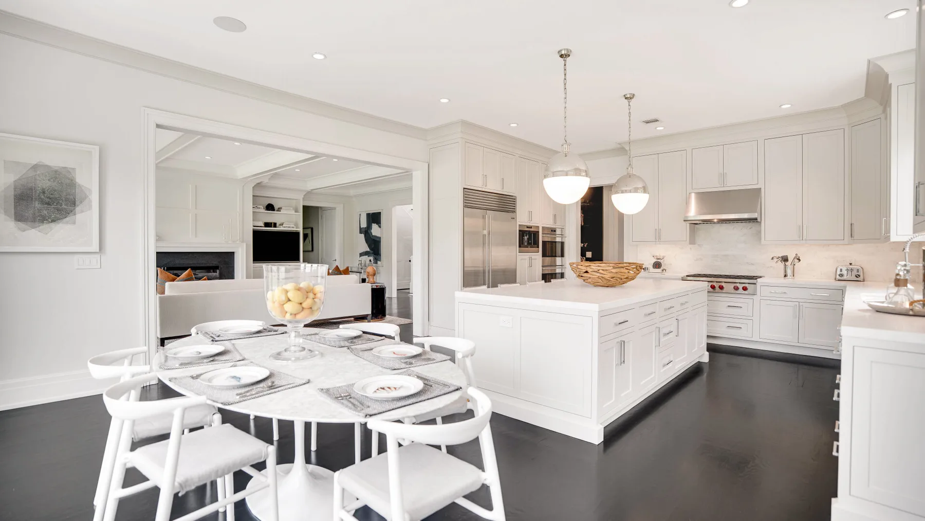 Una cocina blanca y luminosa con una isla central y una mesa de comedor al frente.