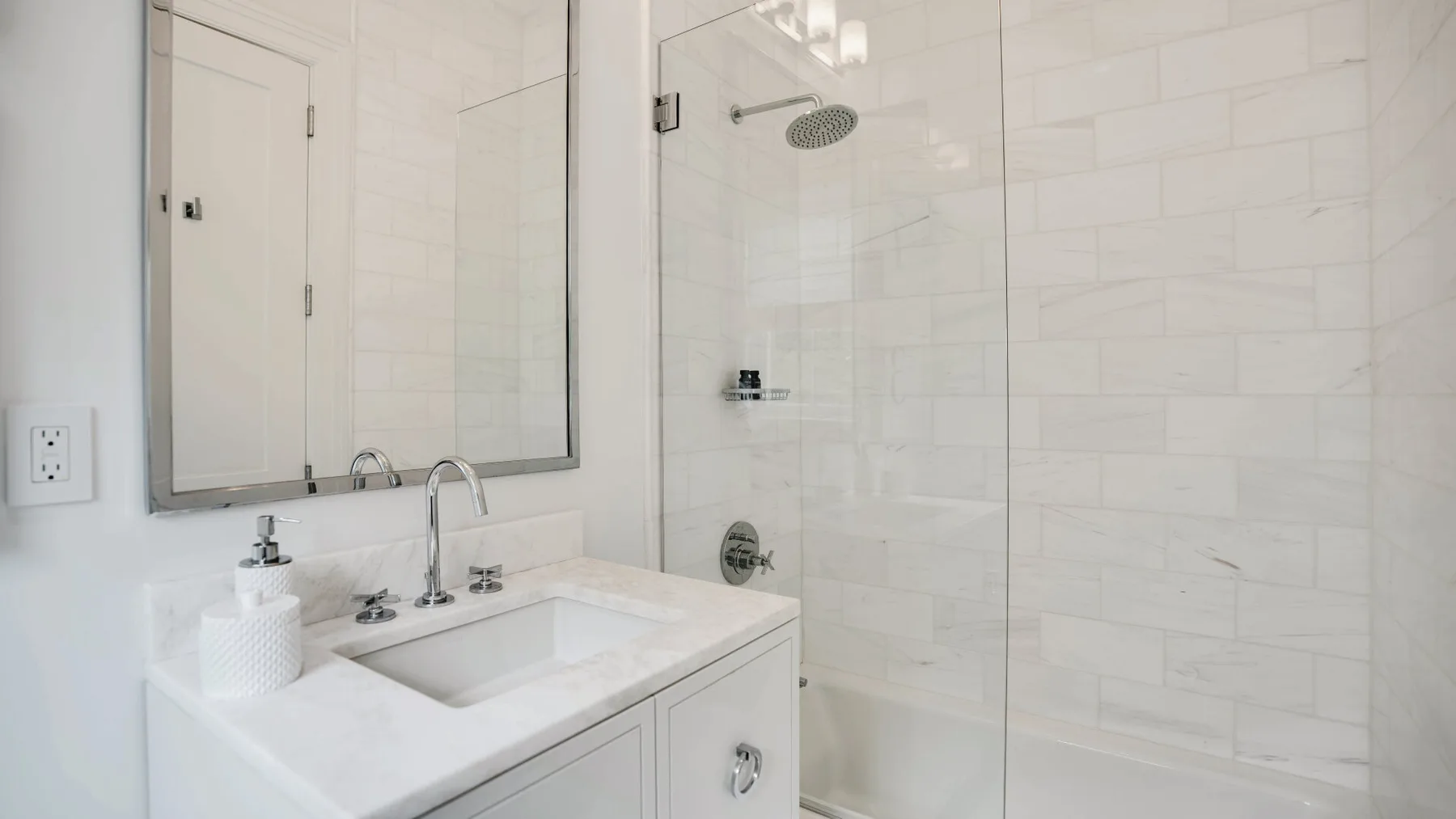 Un tocador de baño con lavabo está junto a una ducha revestida de azulejos.