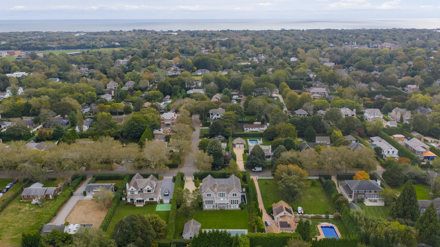 Vista aérea de un barrio residencial arbolado con casas y jardines.