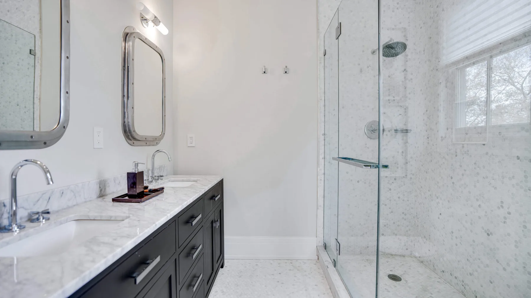 Un baño luminoso con un tocador largo y una ducha de vidrio.
