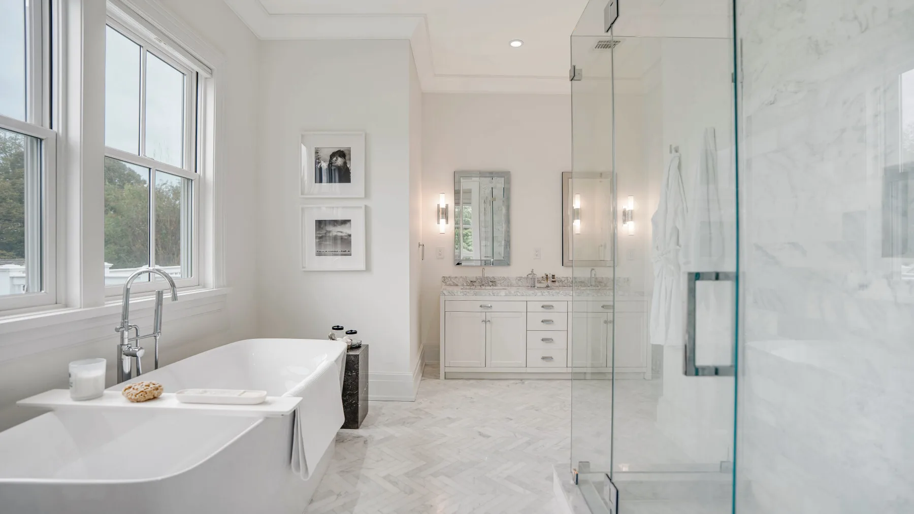 Un baño luminoso con bañera, lavabo y ducha de vidrio.