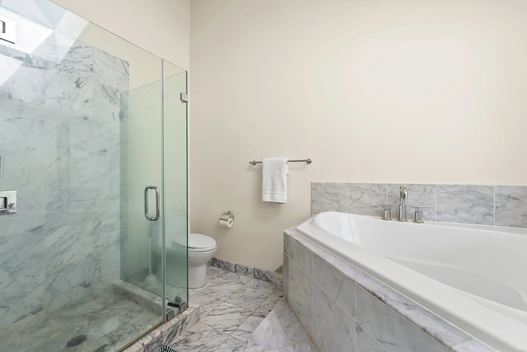 Un baño con una ducha de vidrio y una bañera grande.