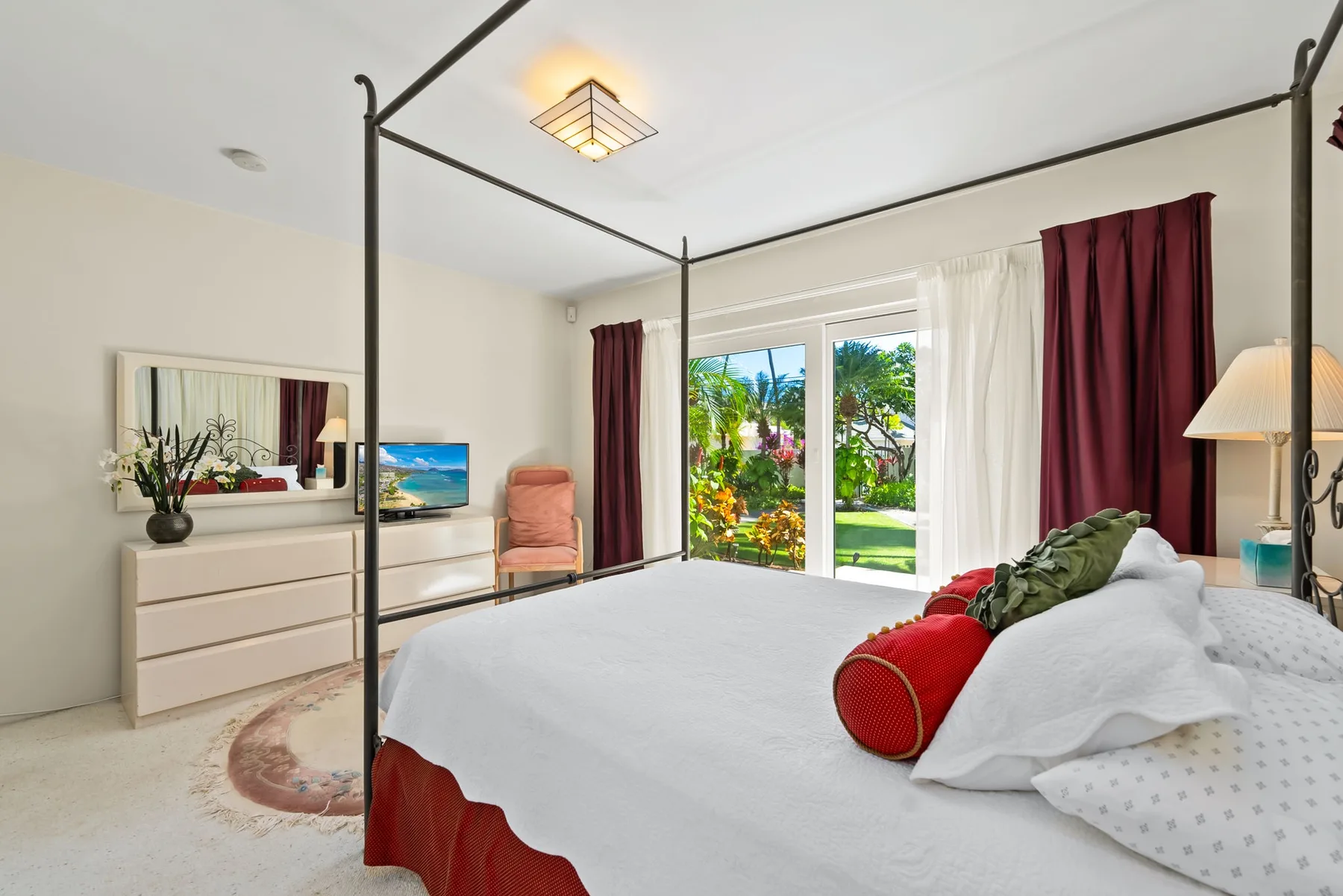 Un dormitorio luminoso con una cama grande y puertas de vidrio que dan a un jardín.