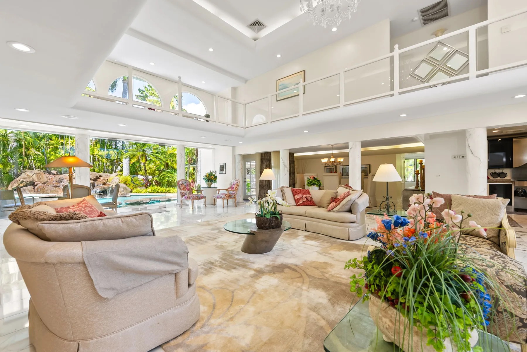 Una sala de estar luminosa con asientos, grandes ventanas y vistas al jardín.