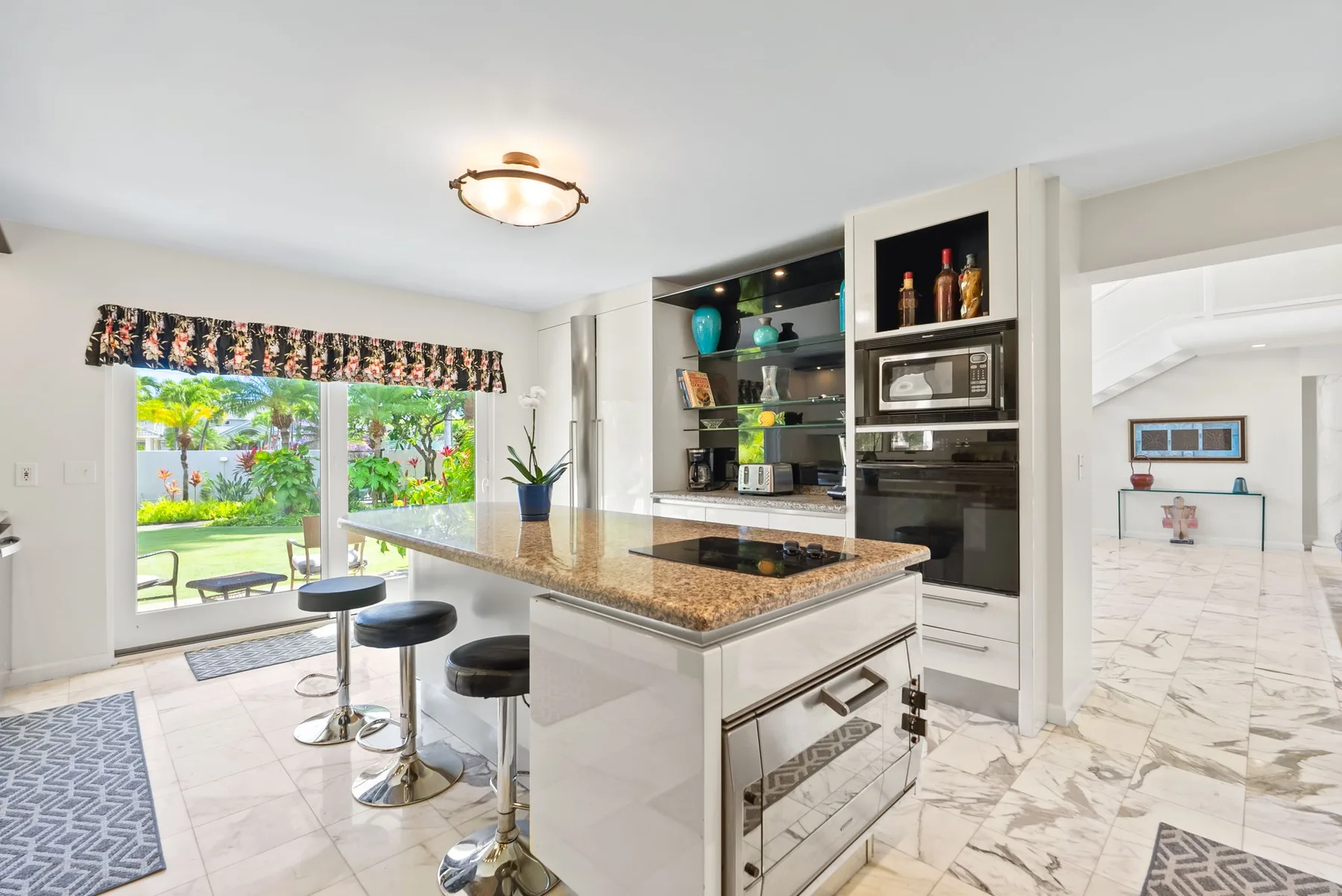Una cocina luminosa con una isla central y puertas de vidrio que dan al jardín.