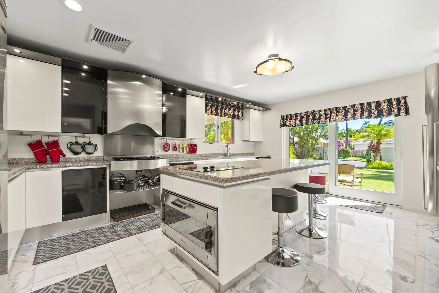 Una cocina luminosa con una isla central y grandes ventanas que dan a un jardín.