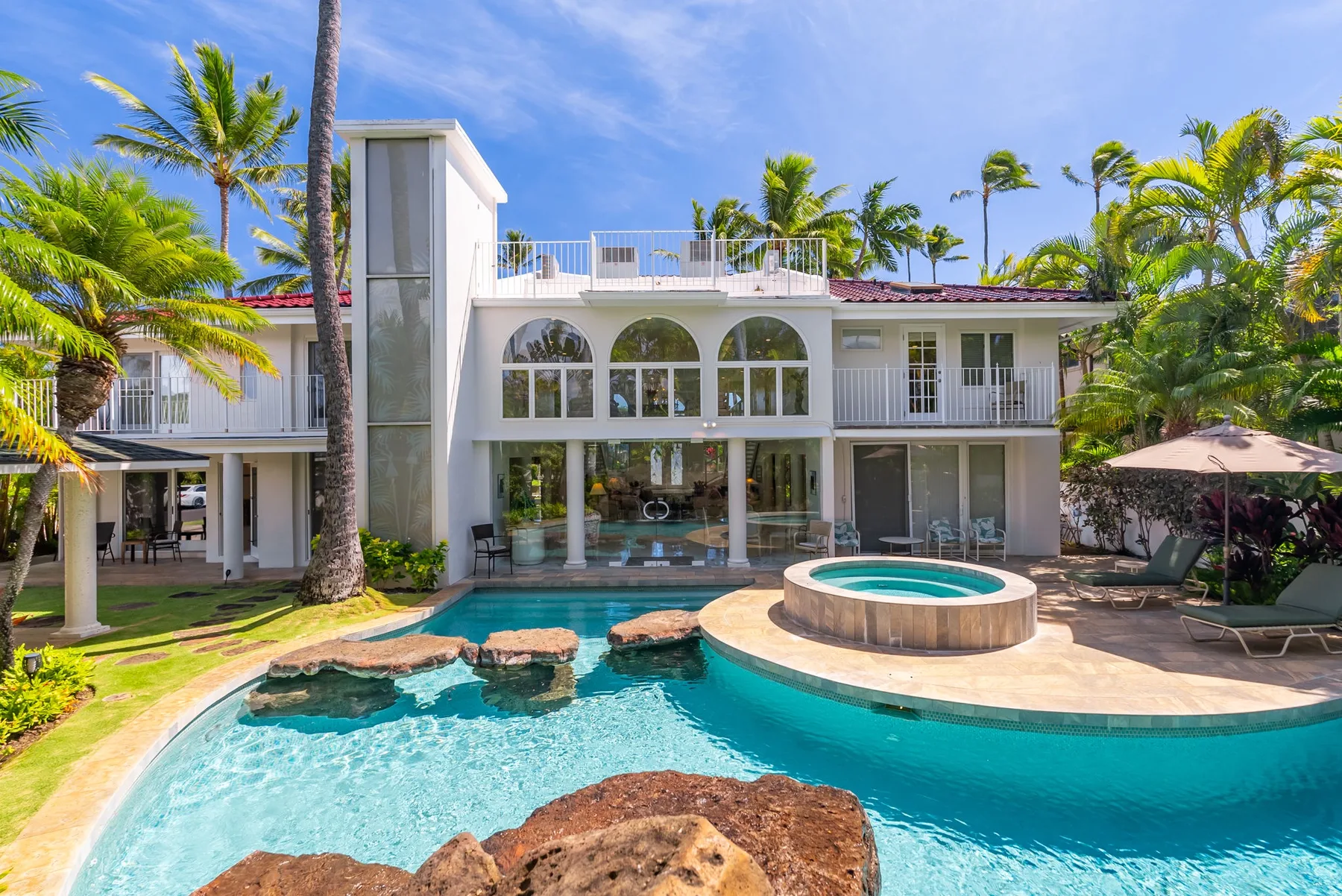 Una casa tropical moderna da a una piscina y un spa circular elevado.