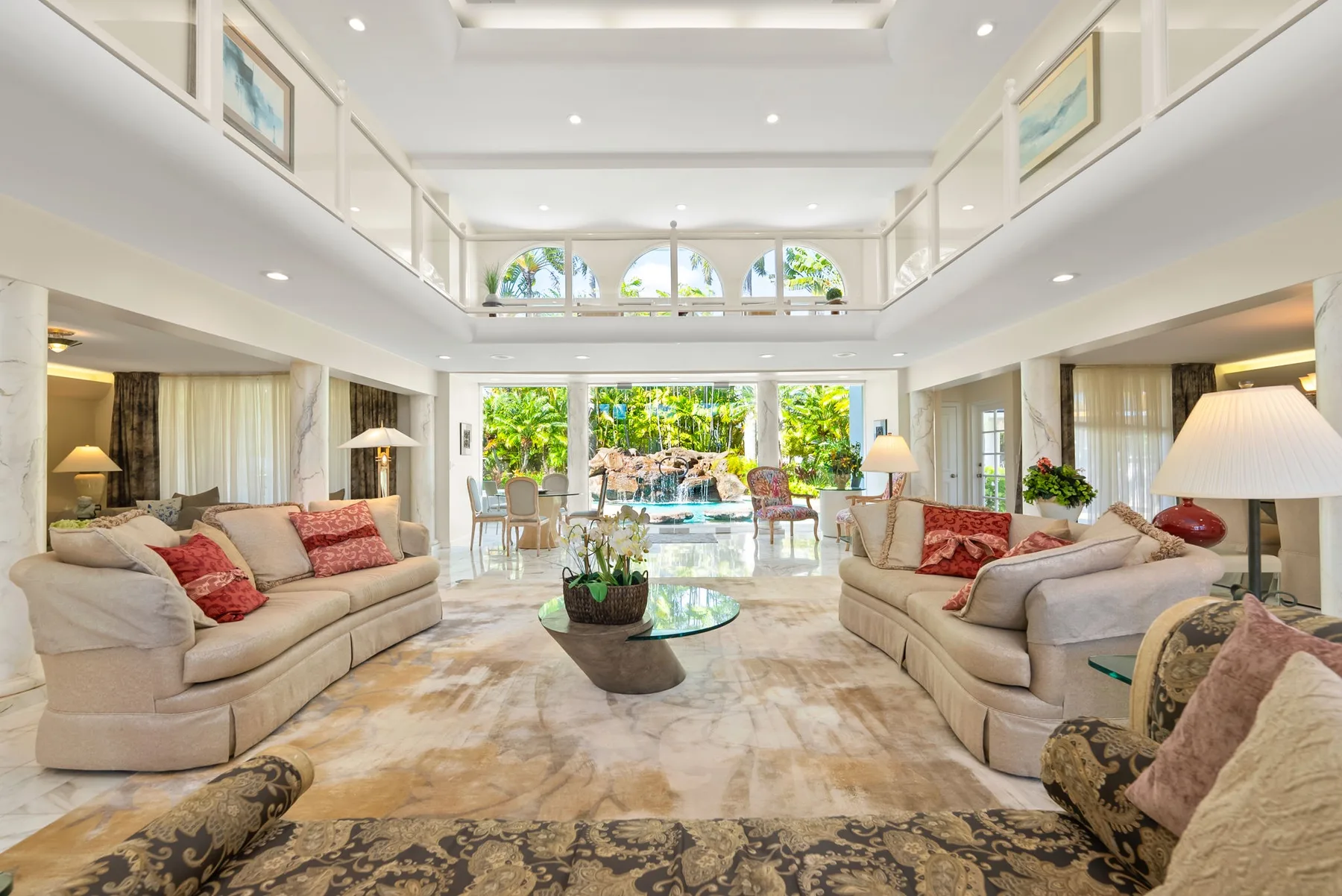 A bright living room with seating arranged around a glass coffee table.