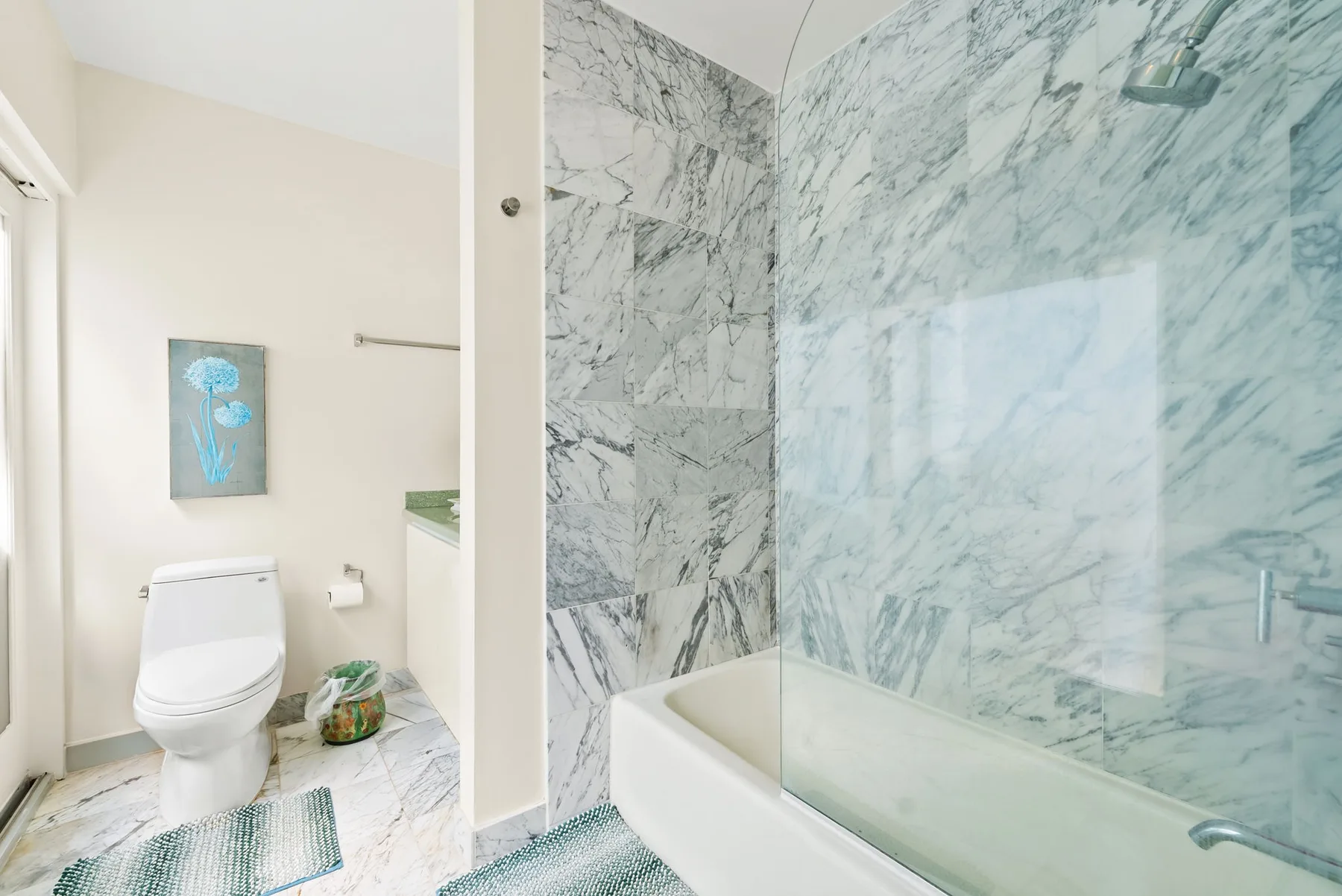 Un baño luminoso con un inodoro y una ducha con panel de vidrio.