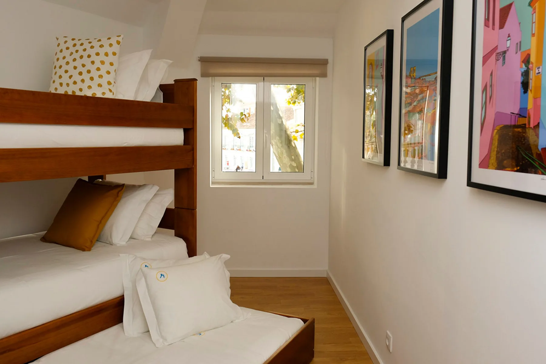 Un dormitorio con una litera de madera, una ventana y cuadros enmarcados.