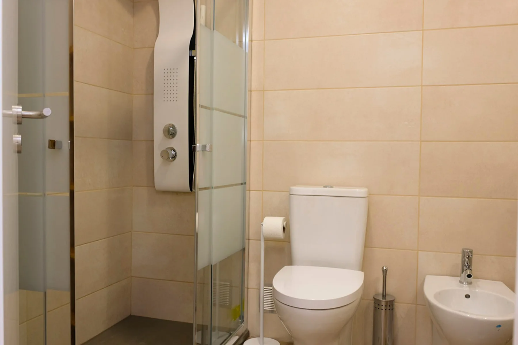 Un baño alicatado con ducha, inodoro y lavabo.
