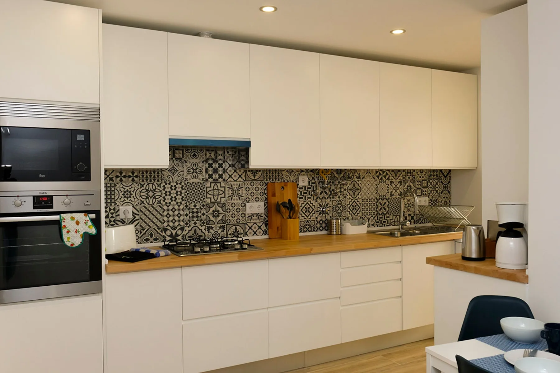 Una cocina moderna con gabinetes blancos y un salpicadero de azulejos estampados.
