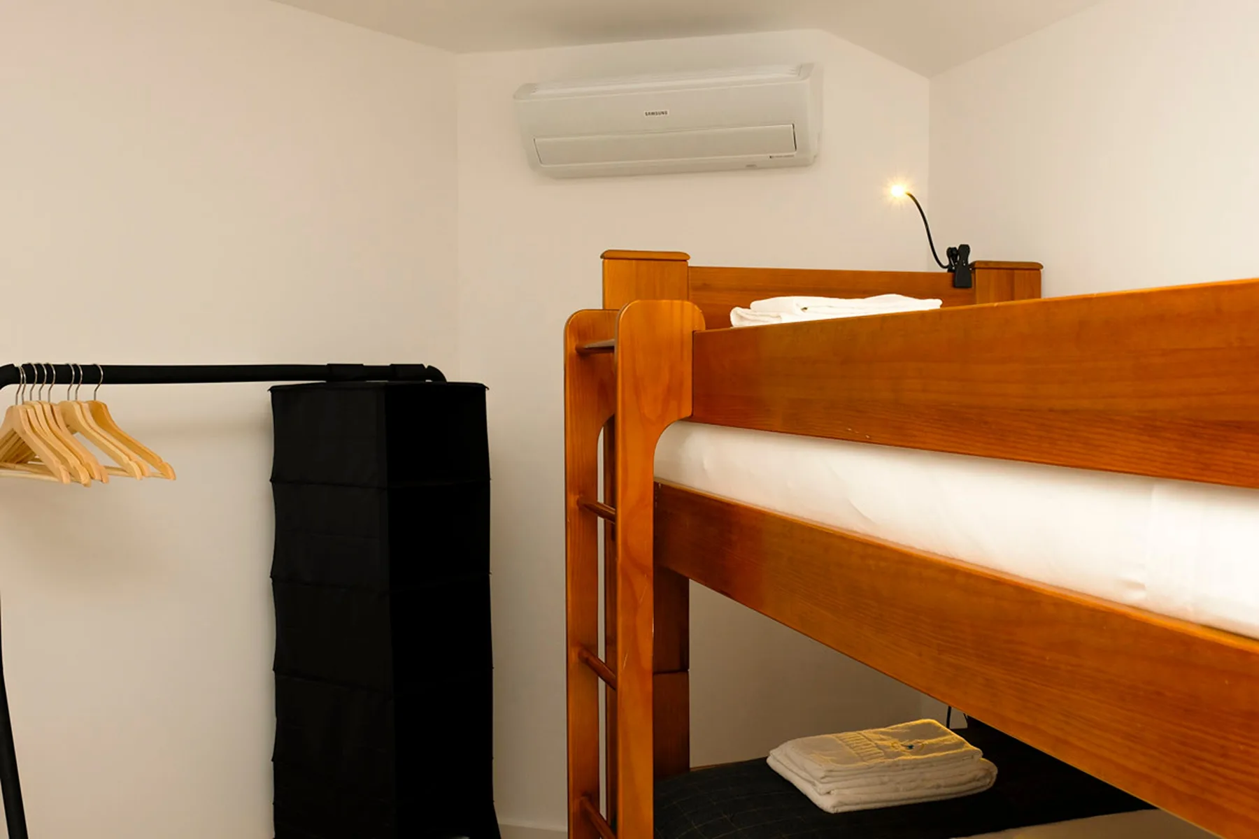 Un dormitorio con una litera de madera y un perchero abierto.