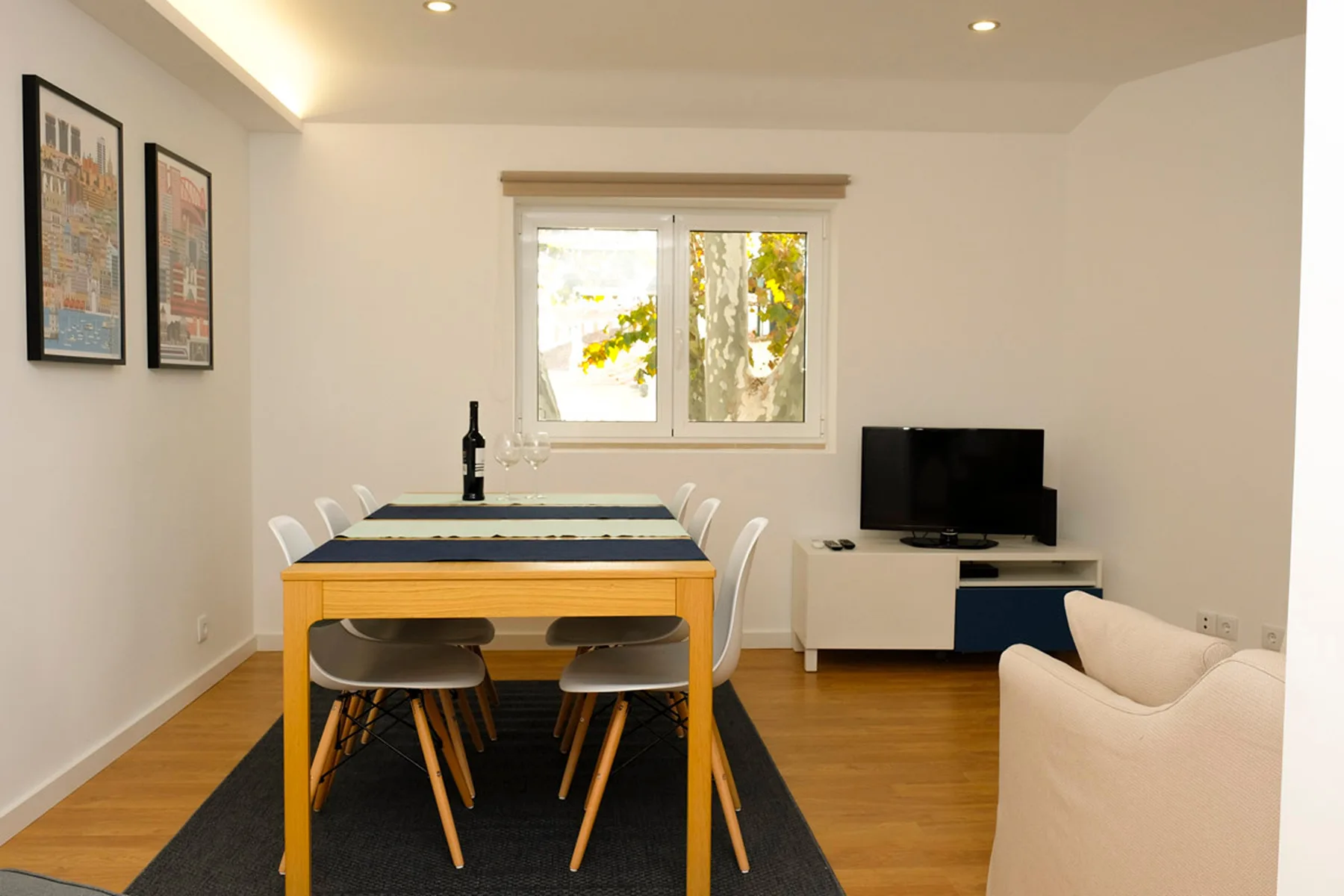 Una zona de comedor y estar con una mesa, asientos y un televisor.