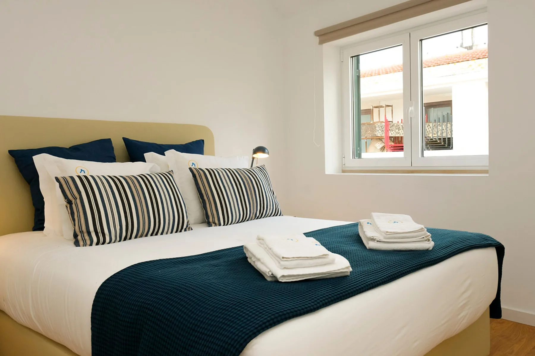 Un dormitorio con una cama bien hecha y una ventana.