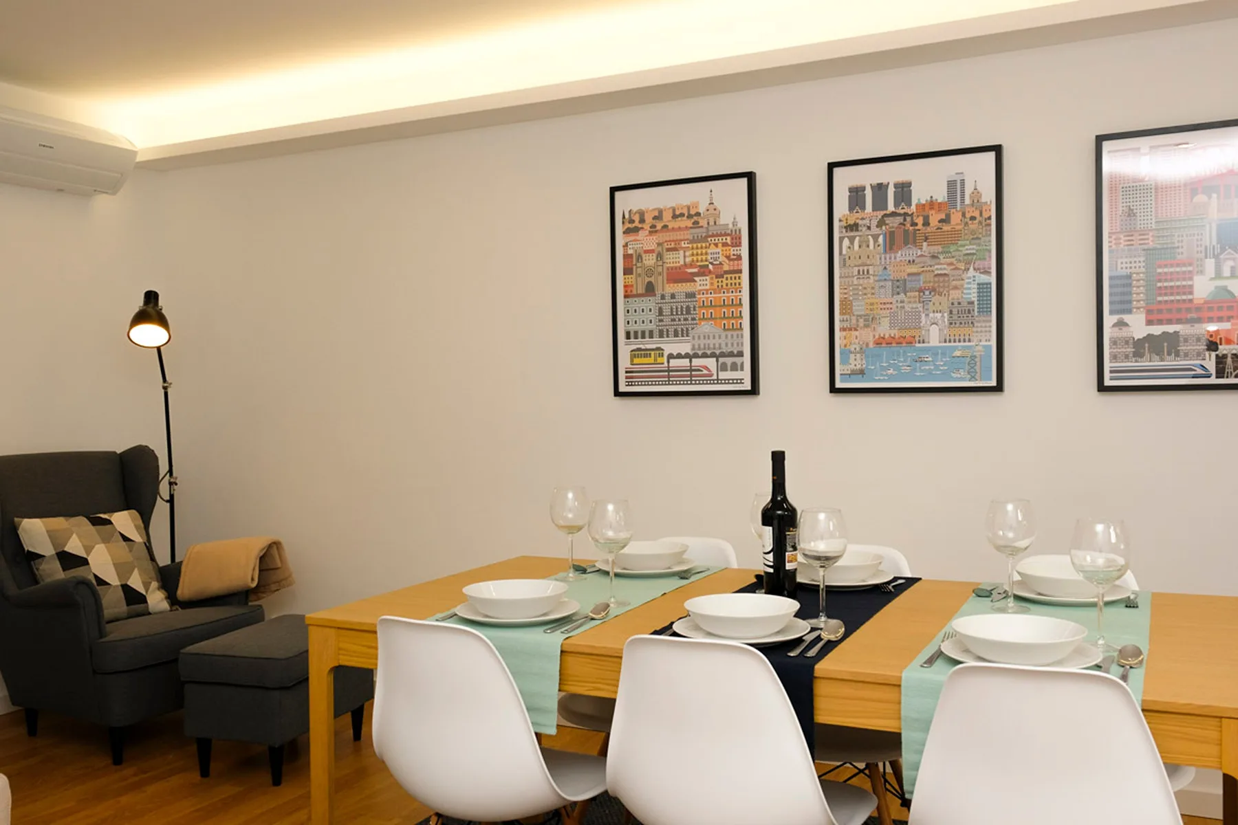 Comedor con una mesa puesta y láminas enmarcadas en la pared.