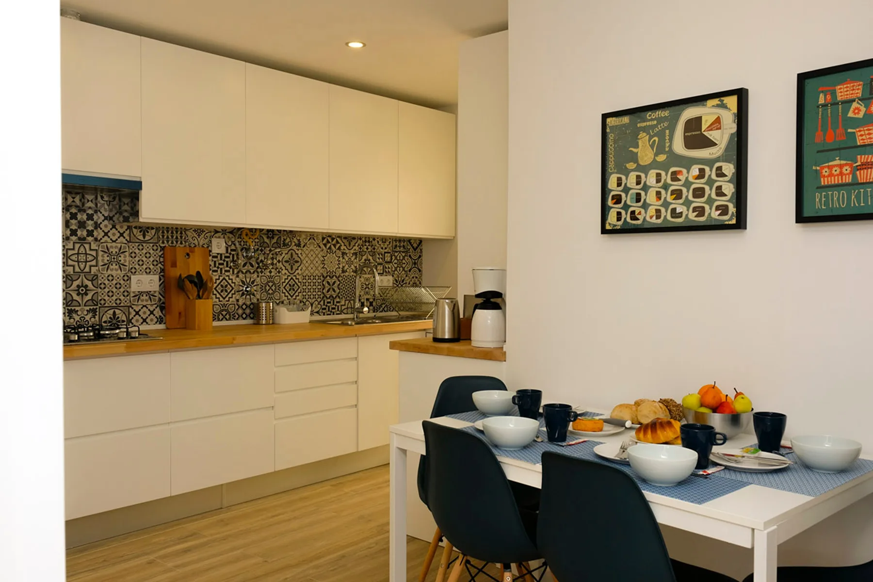 Un comedor con la mesa puesta está junto a una cocina con salpicadero estampado.