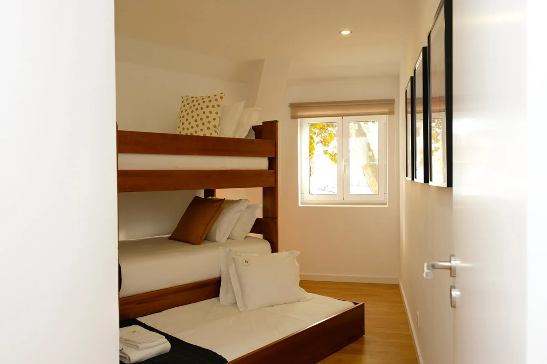 Un dormitorio luminoso con literas de madera y una ventana.