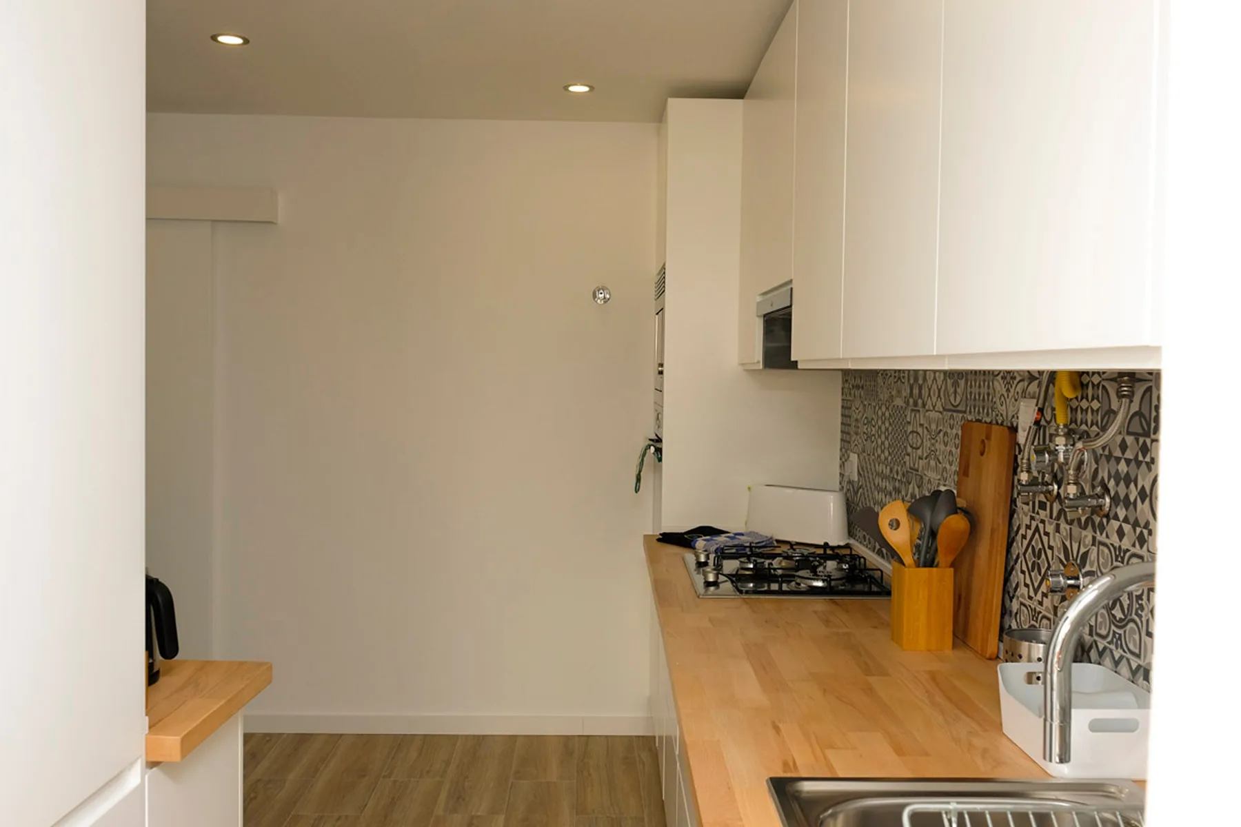 Una cocina compacta con encimeras de madera, una placa de cocción y un fregadero.