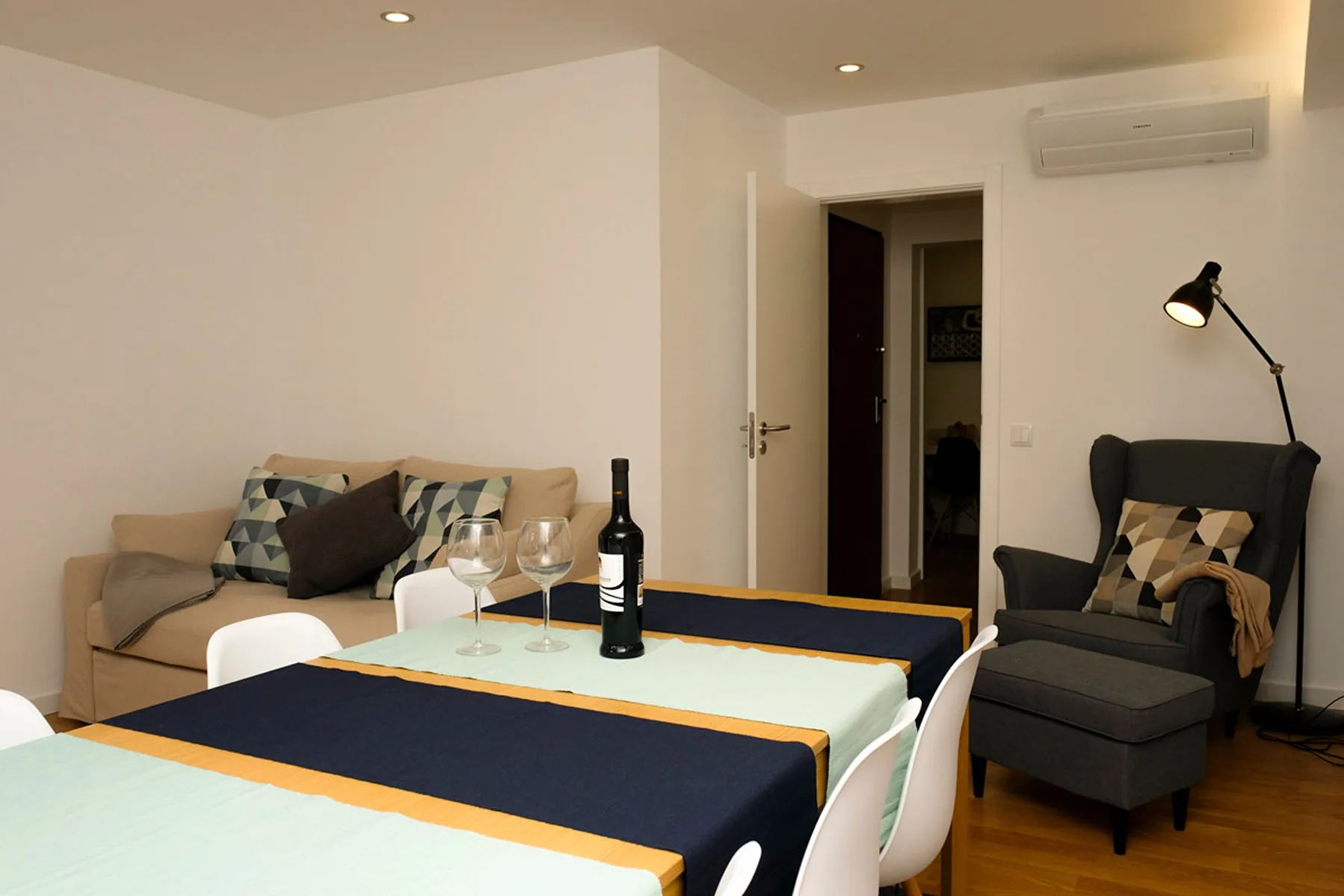 Comedor con la mesa puesta y asientos junto a una zona de estar.