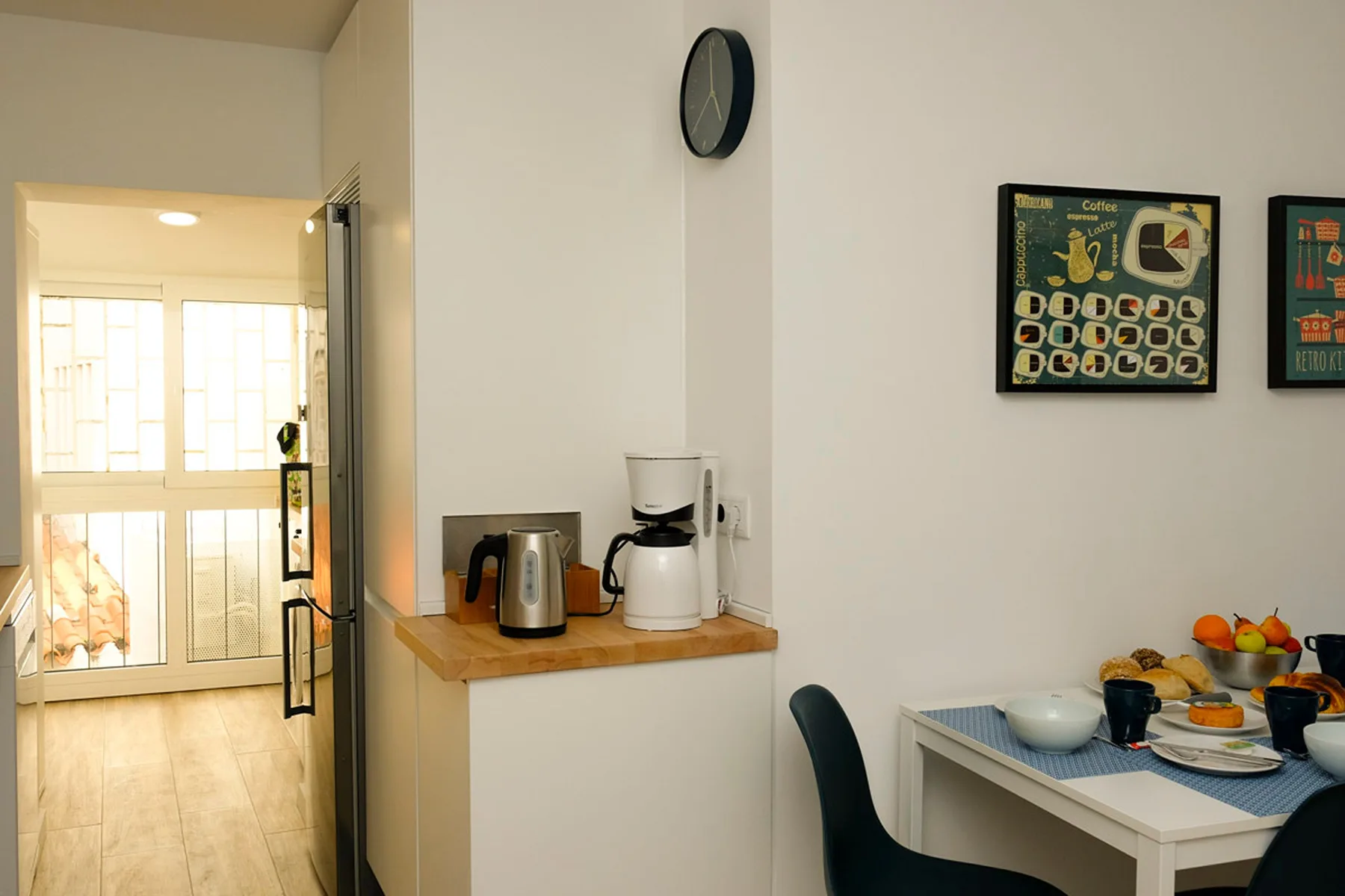 Comedor con una mesa puesta con vajilla junto a una pequeña encimera con electrodomésticos.
