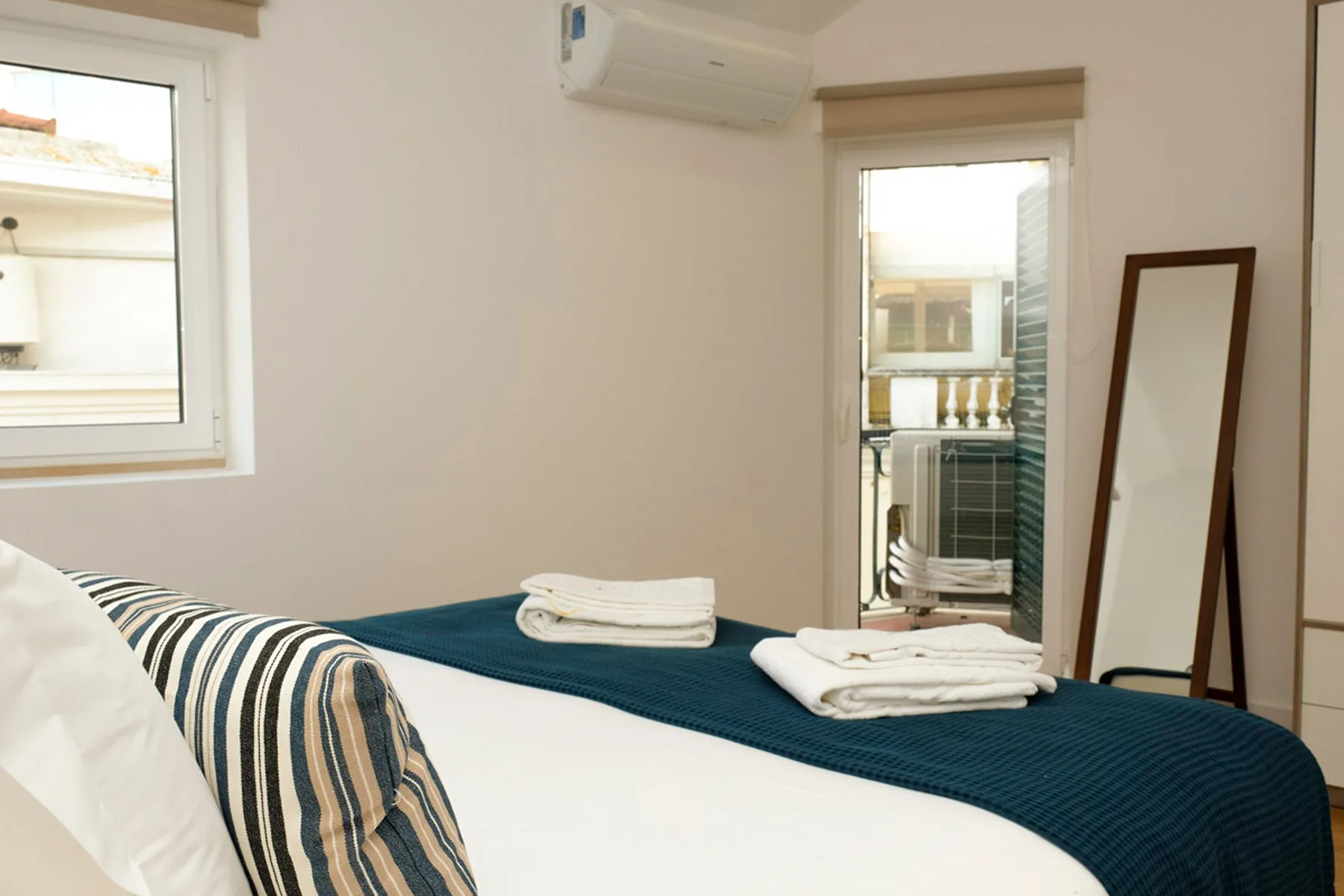 Dormitorio con una cama vestida con sábanas blancas y una colcha azul oscuro.